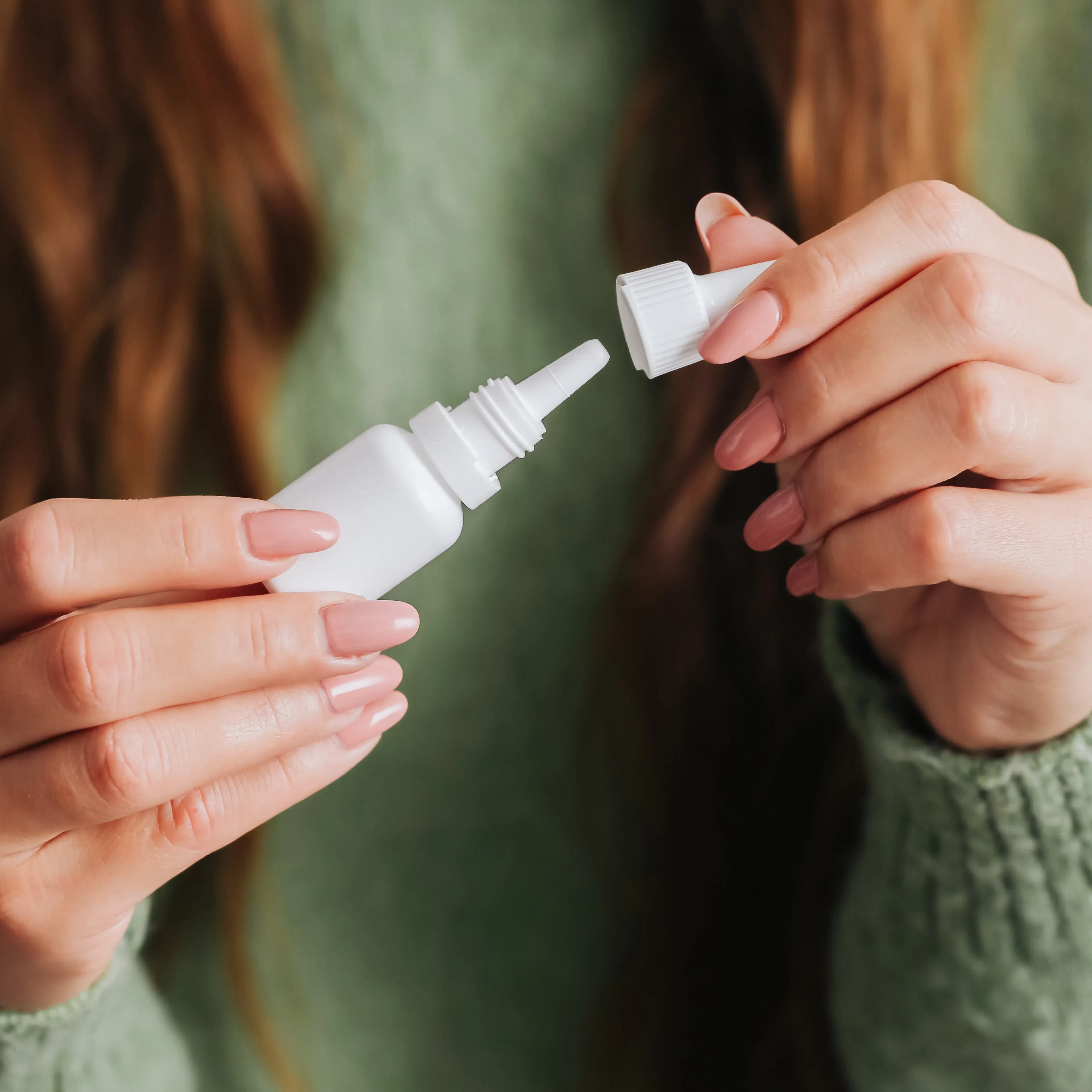 A woman is holding her allergy drops in her hands.