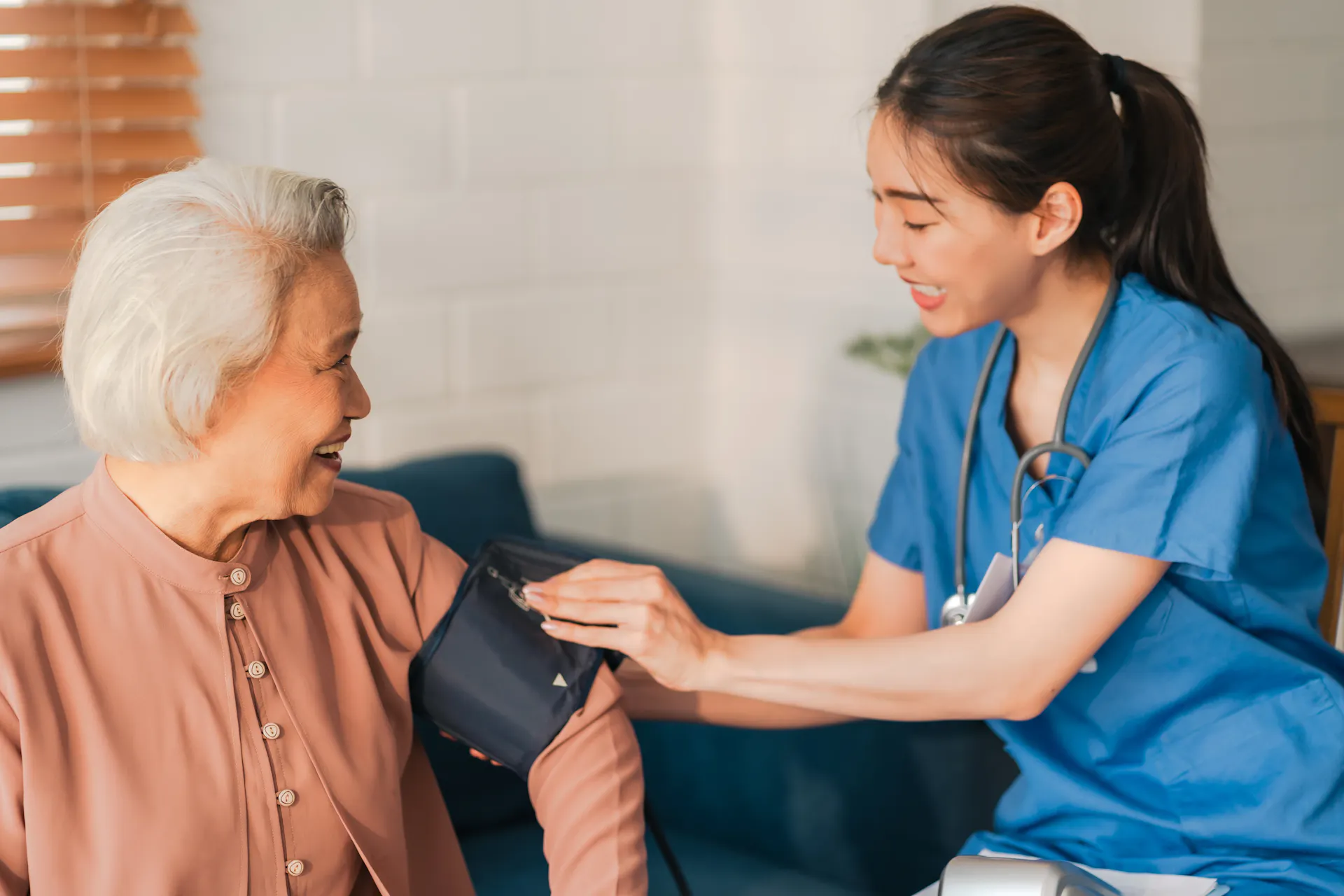 A medical assistant is checking an elderly woman's pressure.