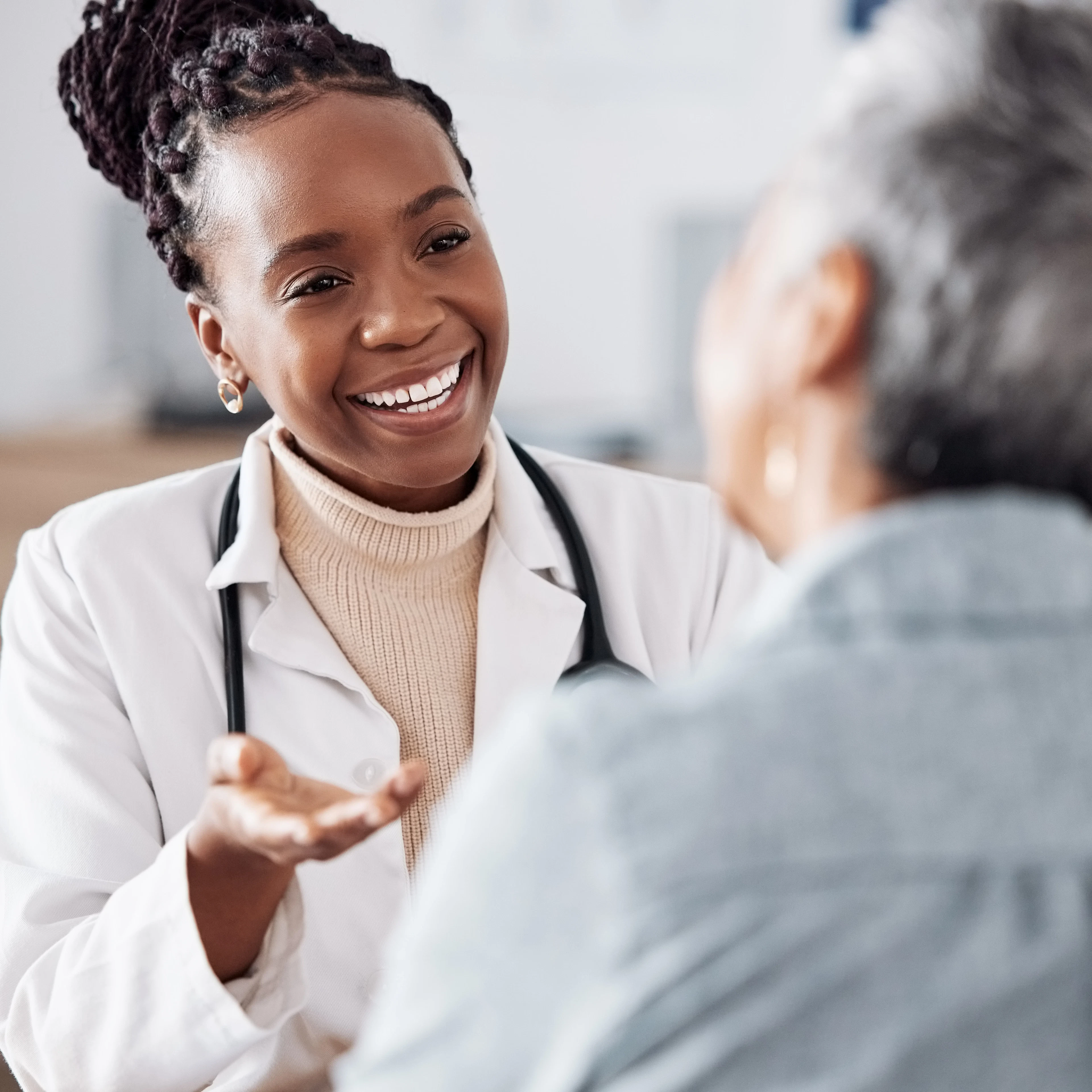 A female doctor is looking at her patient while smiling.
