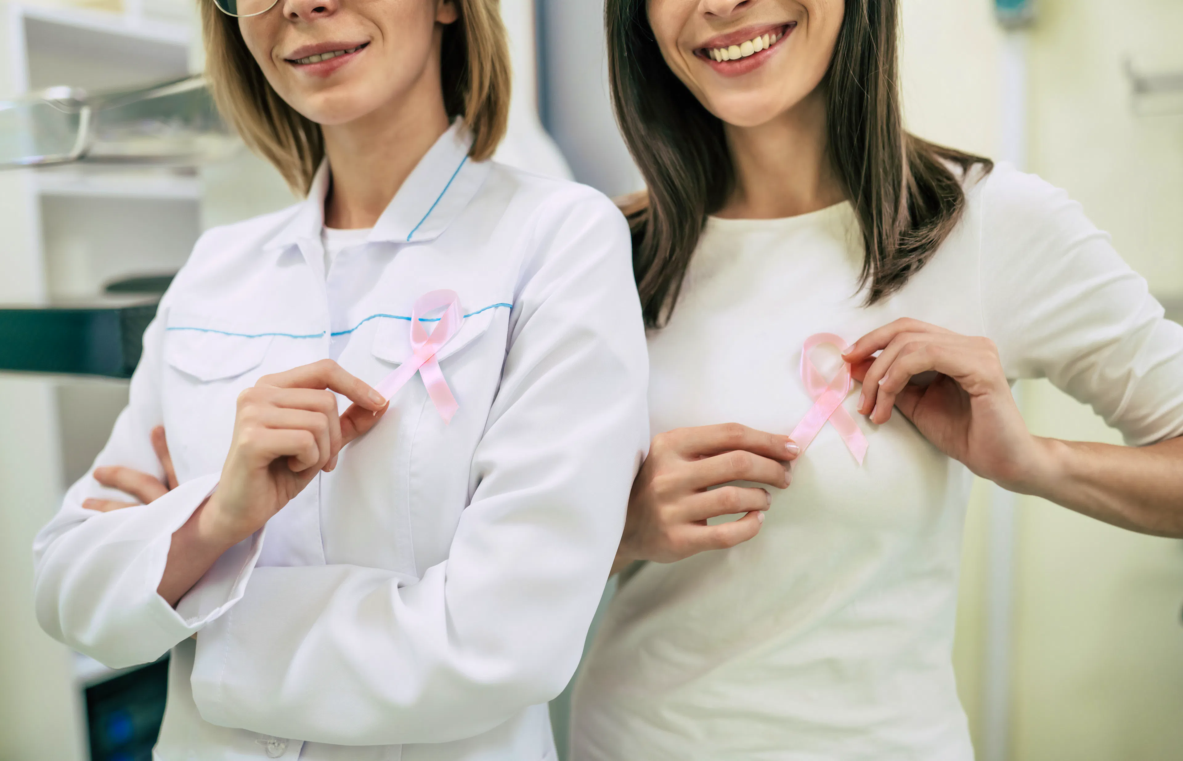 A female doctor and patient are holding up breast cancer ribbons for awareness.
