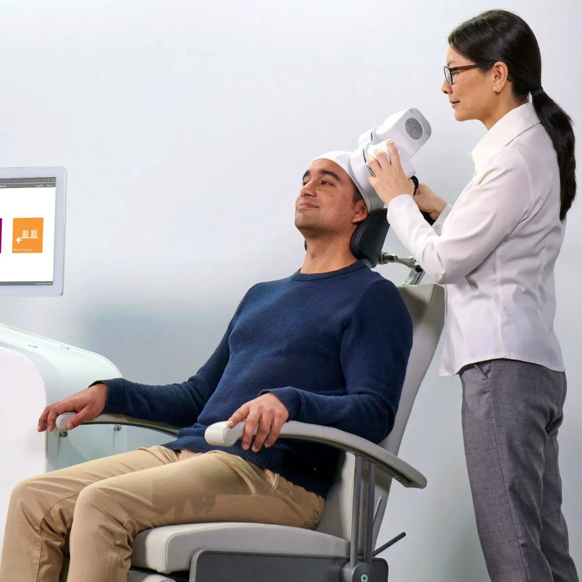 A man is receiving Transcranial Magnetic Stimulation (TMS) therapy to combat depression.