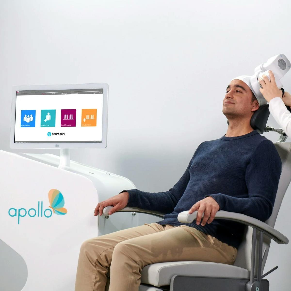 A man is receiving Transcranial Magnetic Stimulation (TMS) therapy to combat depression.