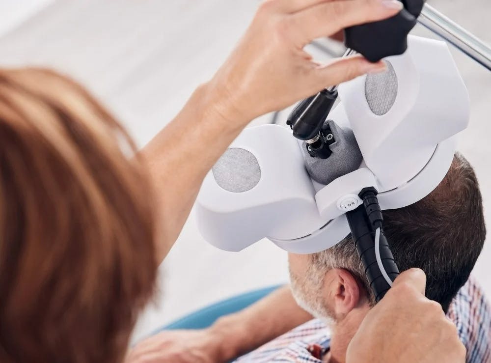 Patient receiving TMS therapy, the headpiece is on the scalp delivering magnetic pulses.