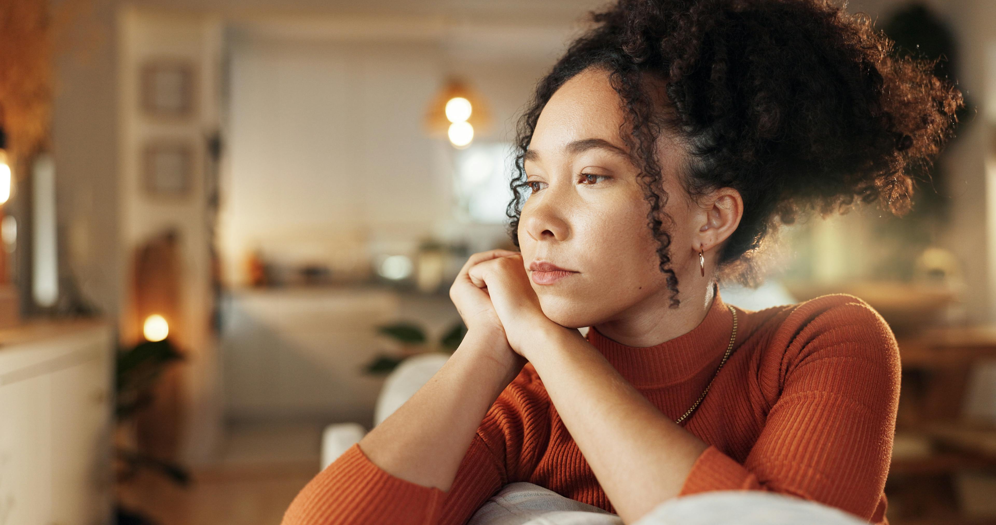A woman is contemplating in her house, looking gloomy.