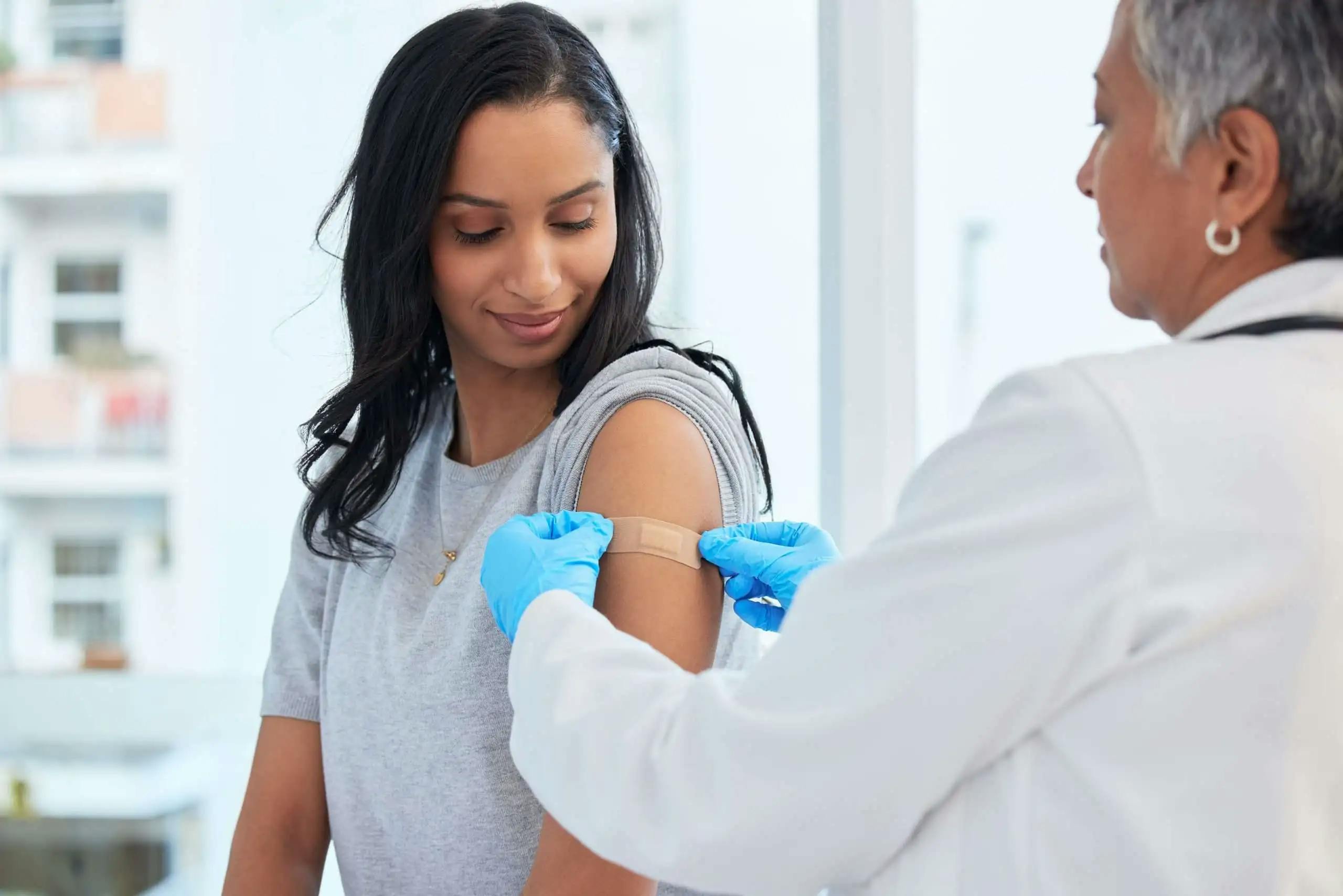 Young woman receiving a flu shot from a healthcare professional in a clinic, promoting flu prevention and health care during flu season.