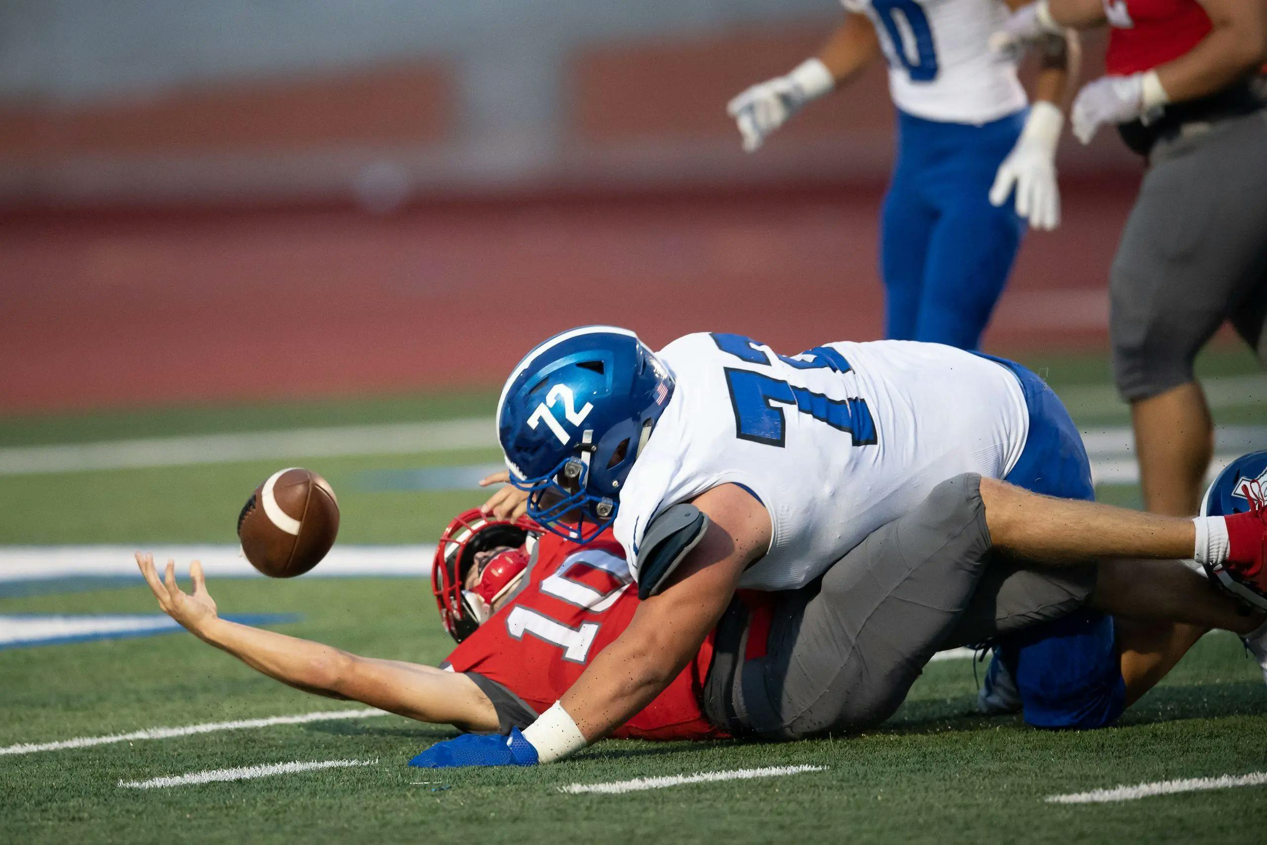 An intense high school football game , showing players in action. The scene emphasizes the risks of the 'no pain, no gain' mindset in youth sports.