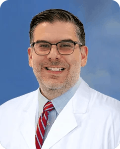 Professional headshot of Dr. Javier Rios, MD, a sports medicine doctor. He is smiling warmly, wearing a white coat.