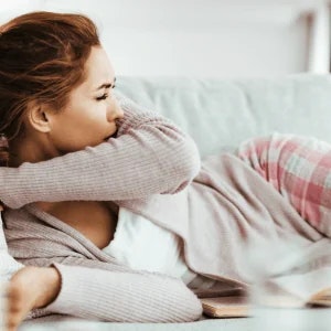 A woman lying on her side, covering her mouth with her arm.