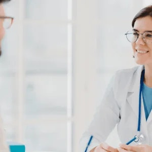 Female healthcare provider in a white coat smiling at a patient.