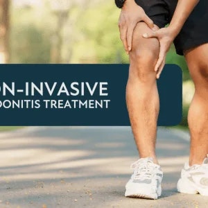 A male's hands clutching his thigh and knee area.