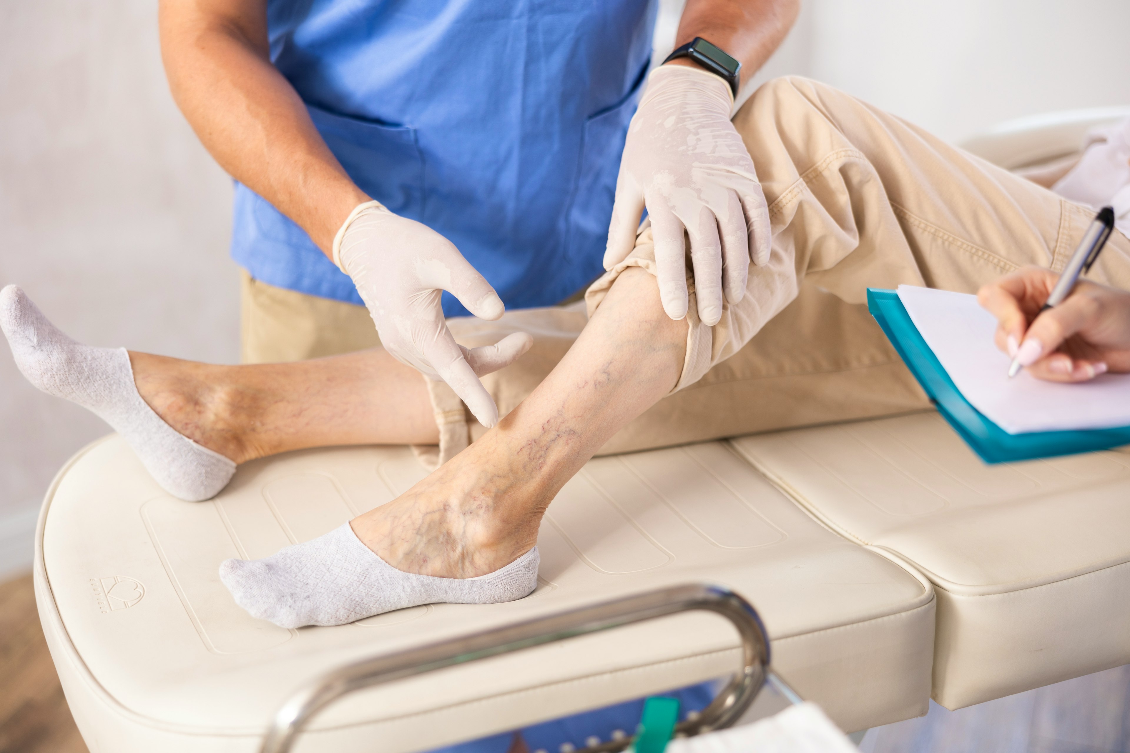 A medical professional is examining the blood vessels on a patient's lower leg as she lay supine.