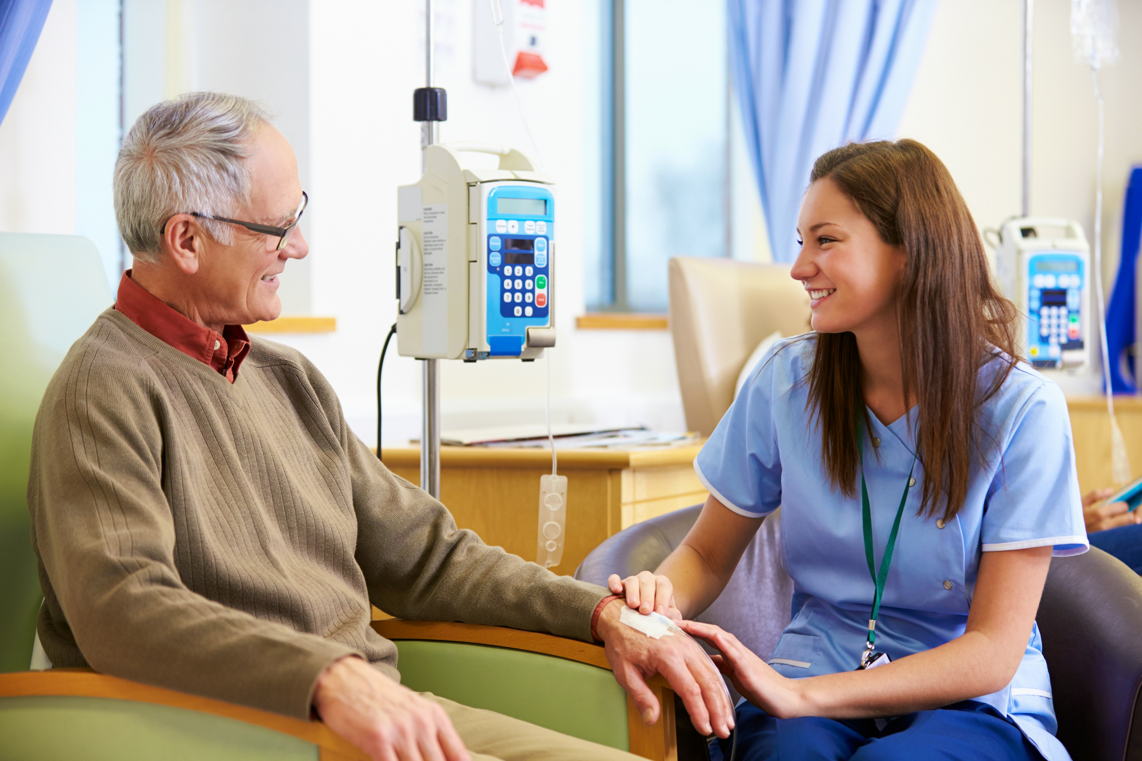 An oncology specialist placing a bandage on a patient's hand after treatment.