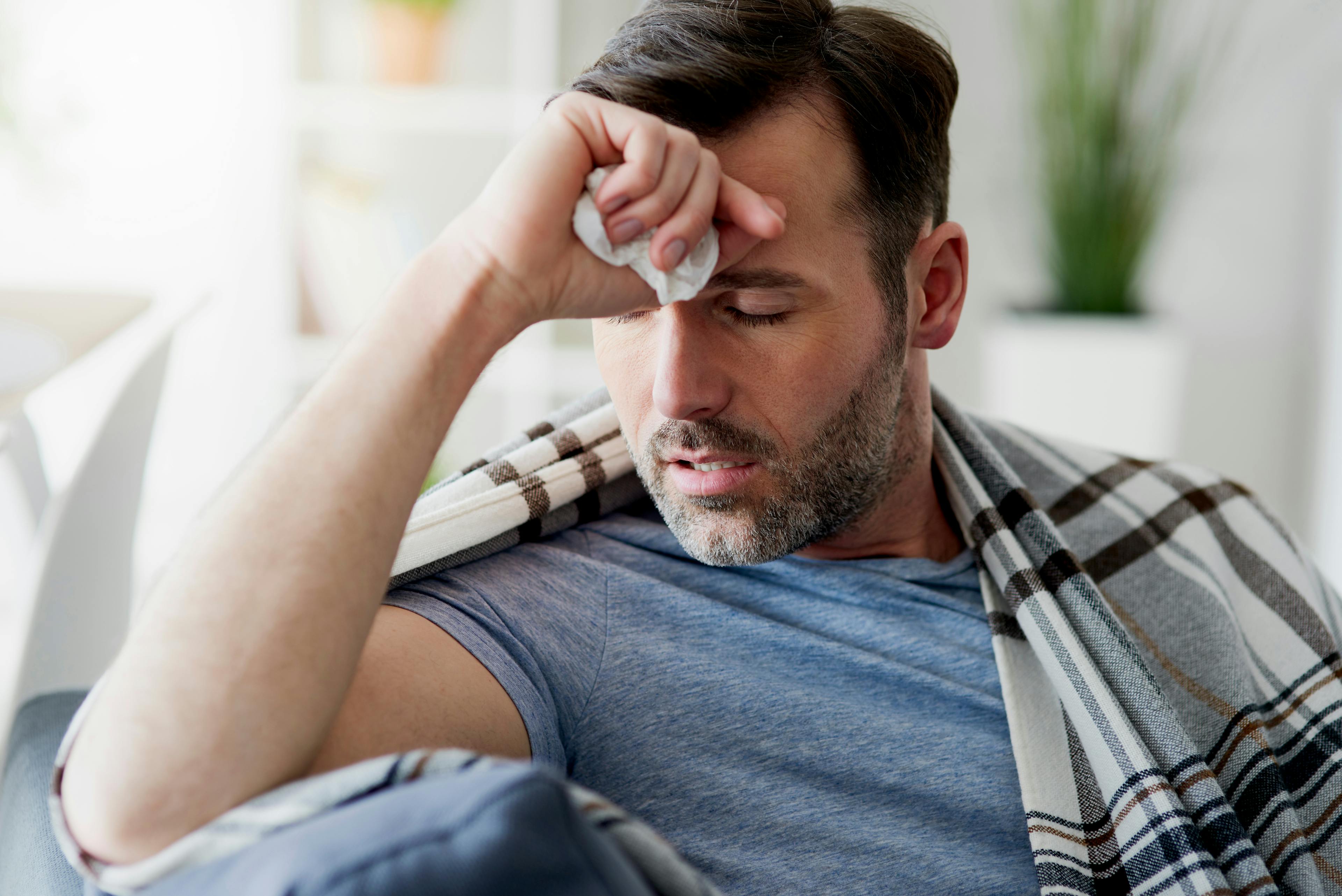 A man resting with his eyes shut and pressing his fist to his forehead.