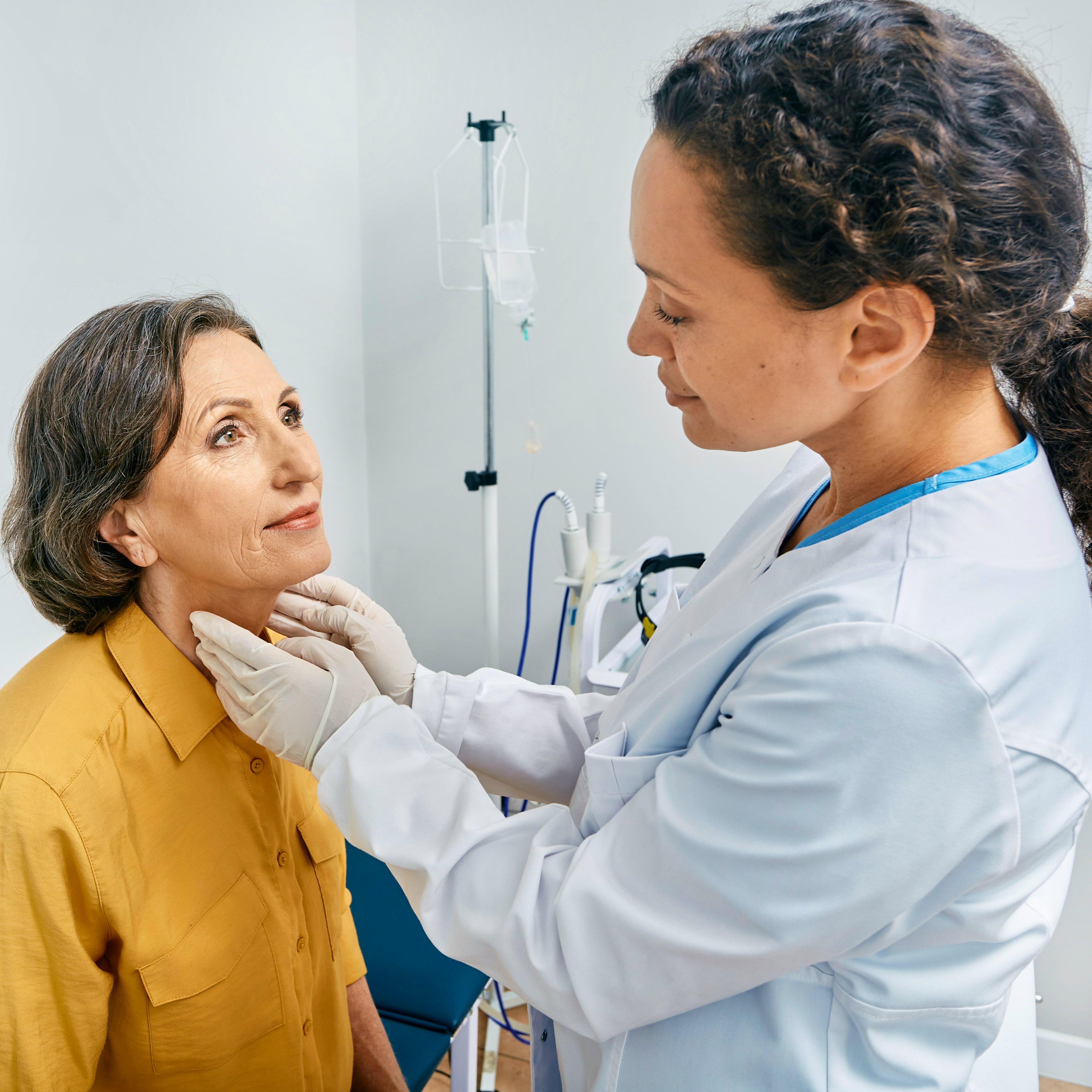 Doctor examining a woman's neck for thyroid diagnostics and hypothyroidism treatment at a medical clinic.