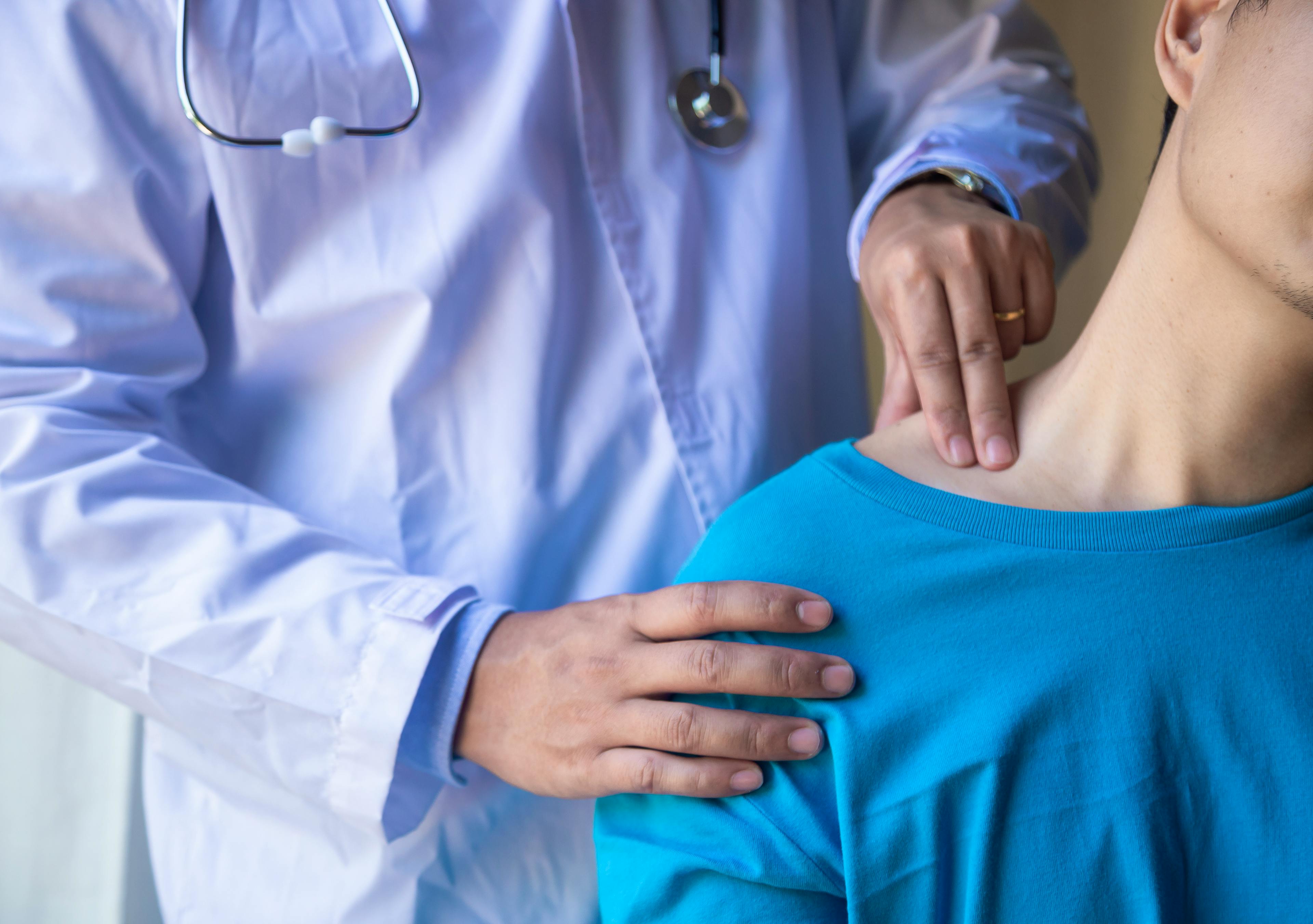 A physician conducing a physical examining a female patient's shoulder region. 