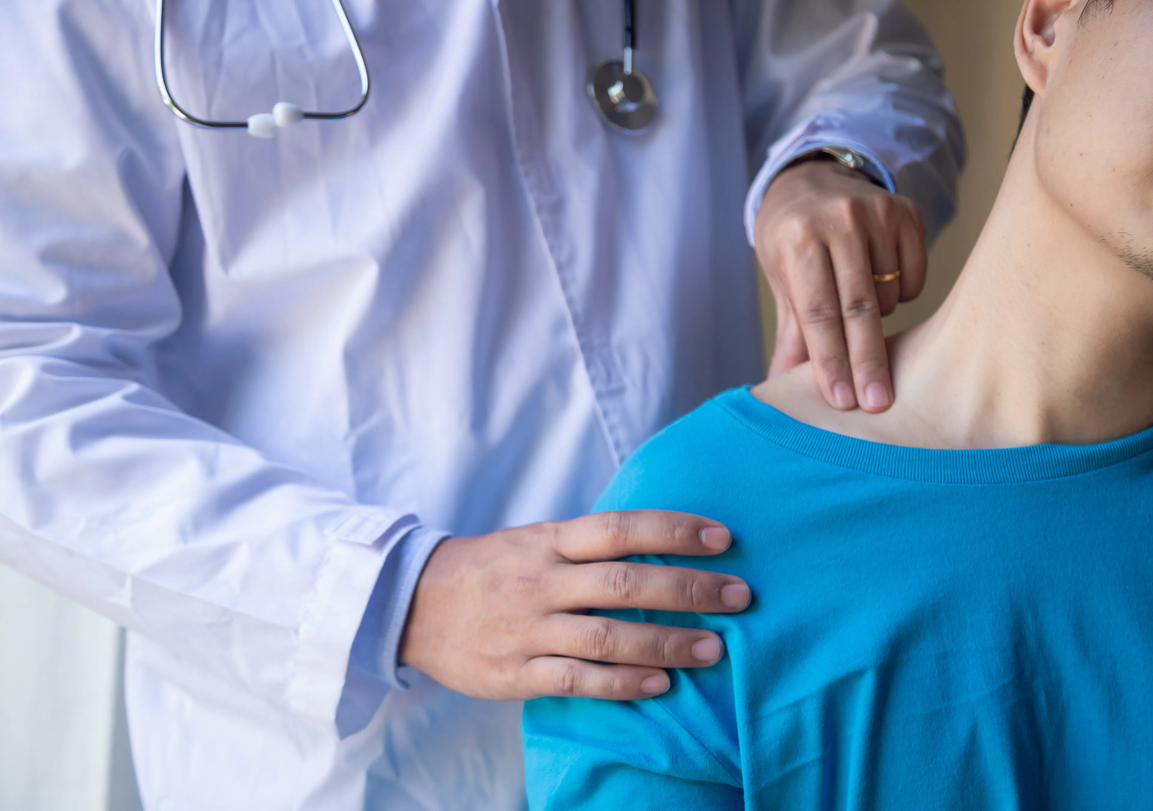 A physician conducing a physical examining a female patient's shoulder region. 