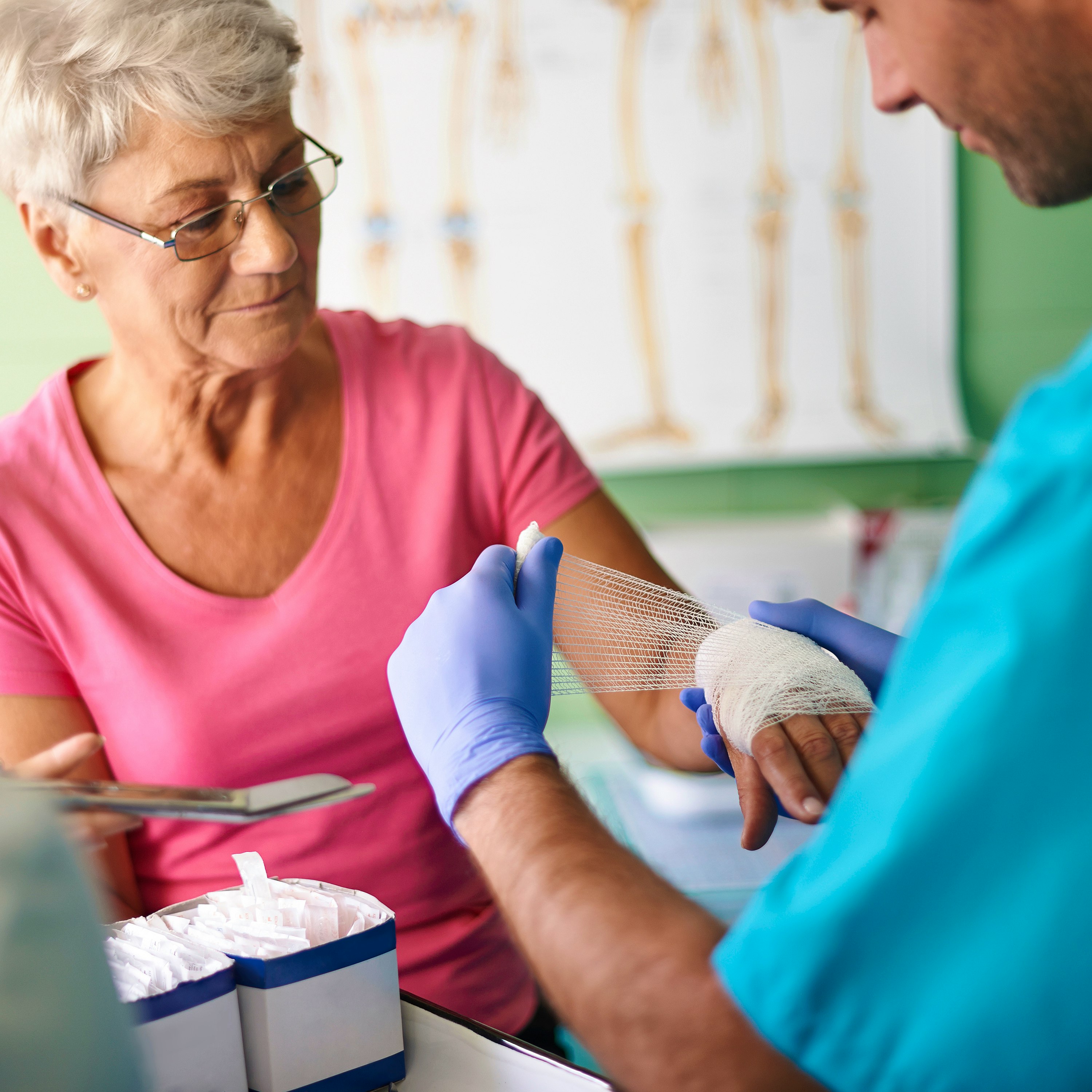 Doctor examining a patient's leg for wound care treatment in a clinical setting.