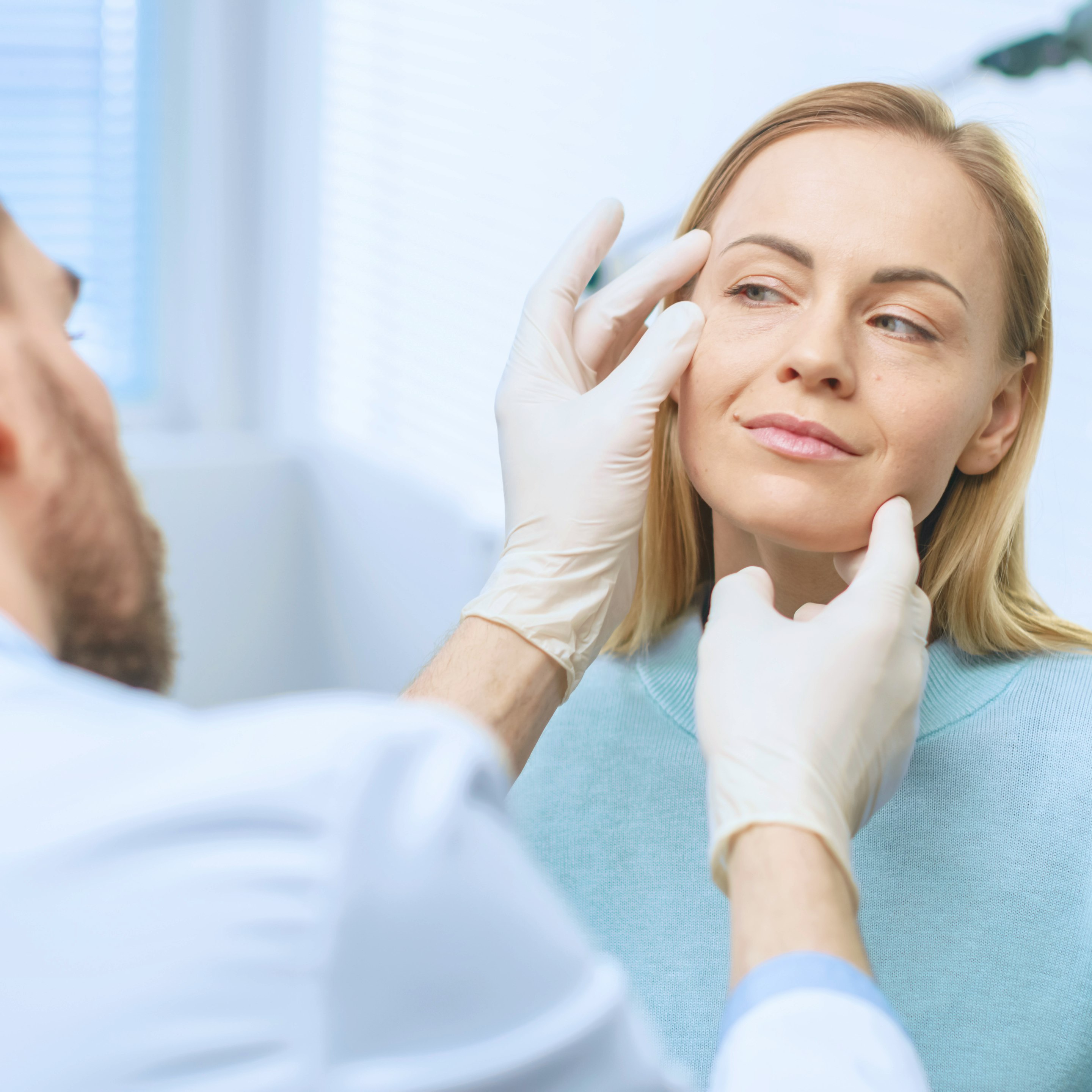 Plastic surgeon examining a patient's face during a consultation for cosmetic or reconstructive surgery.