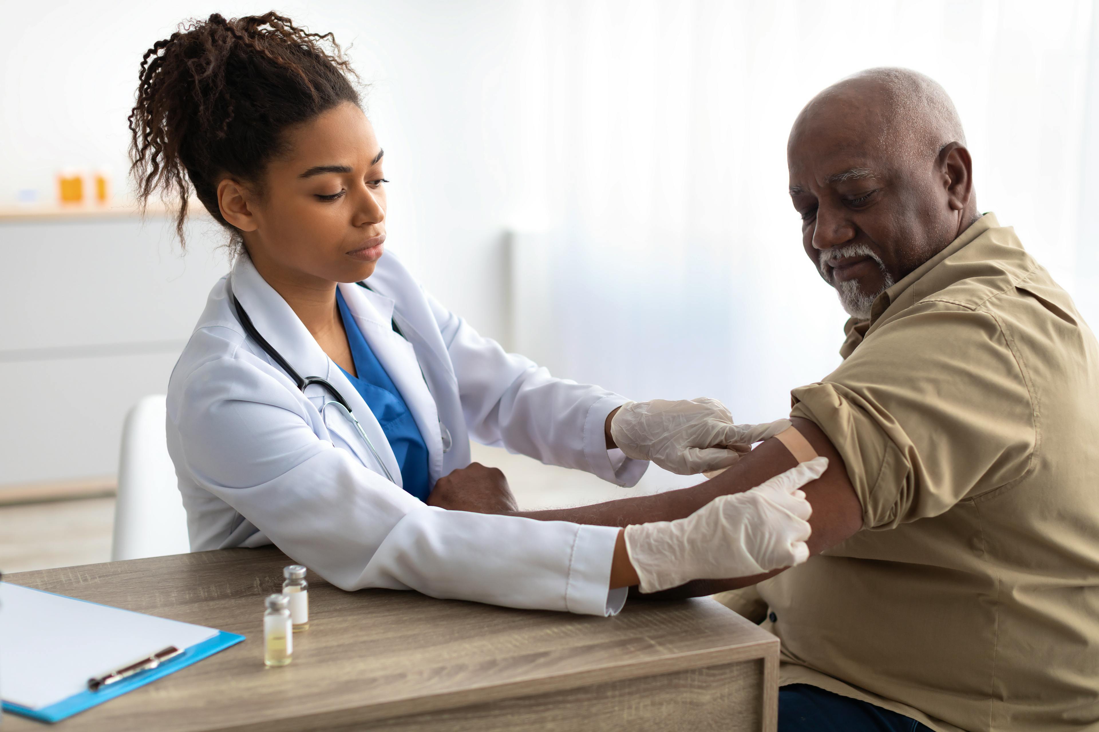 A healthcare provider placing a bandaid on a patient after vaccination.