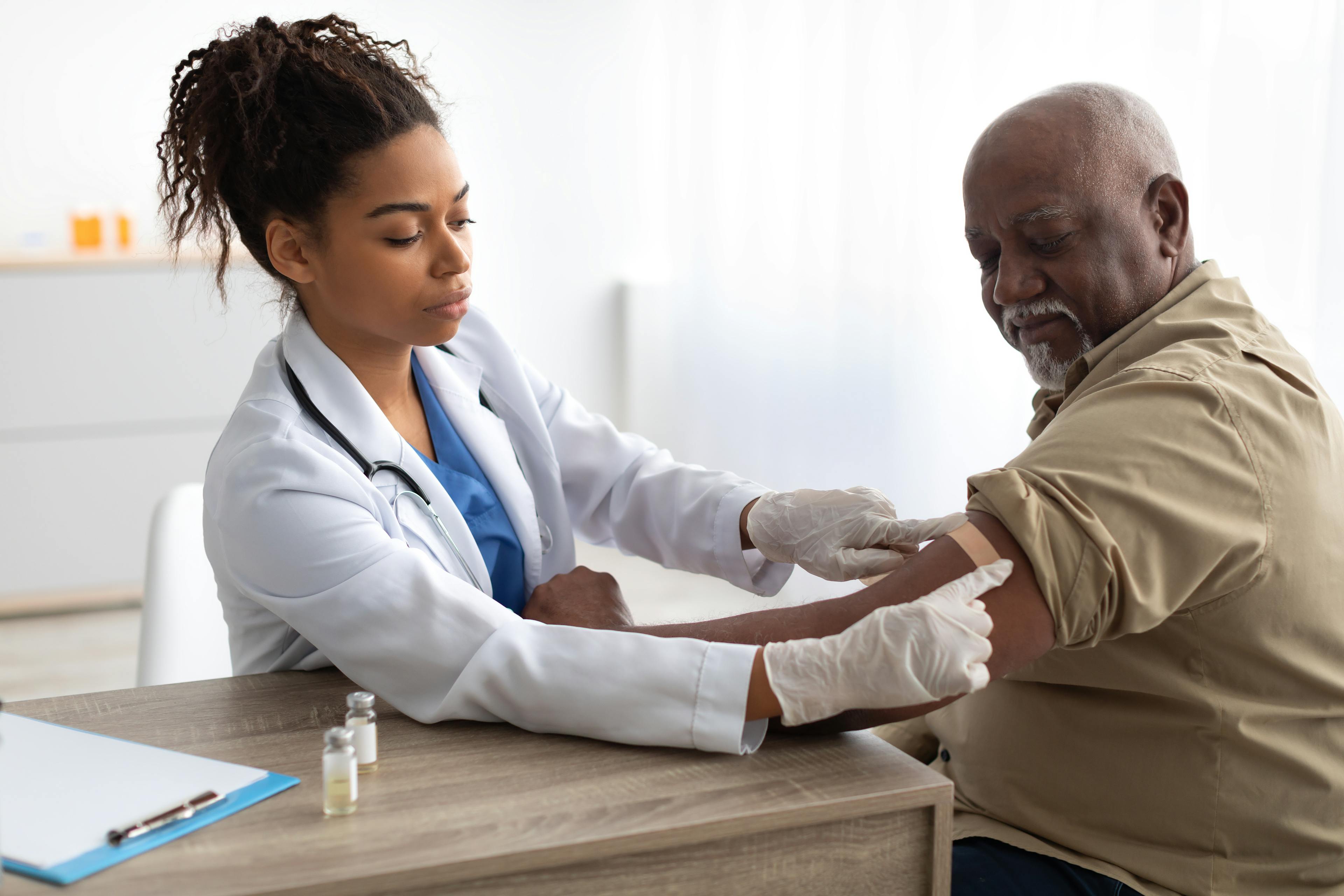 A healthcare provider placing a bandaid on a patient after vaccination.