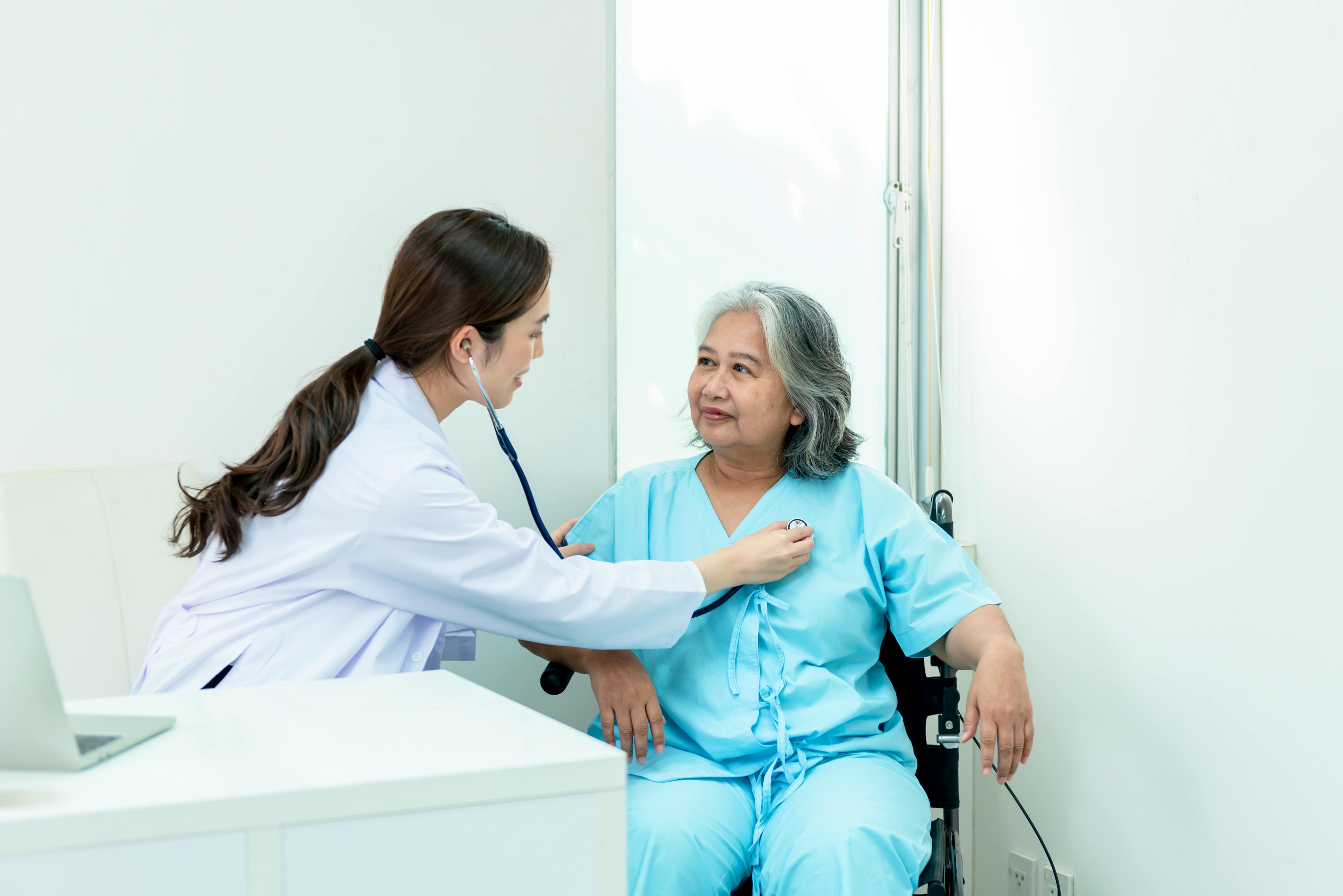 A female physician using stethoscope to examine female patient.
