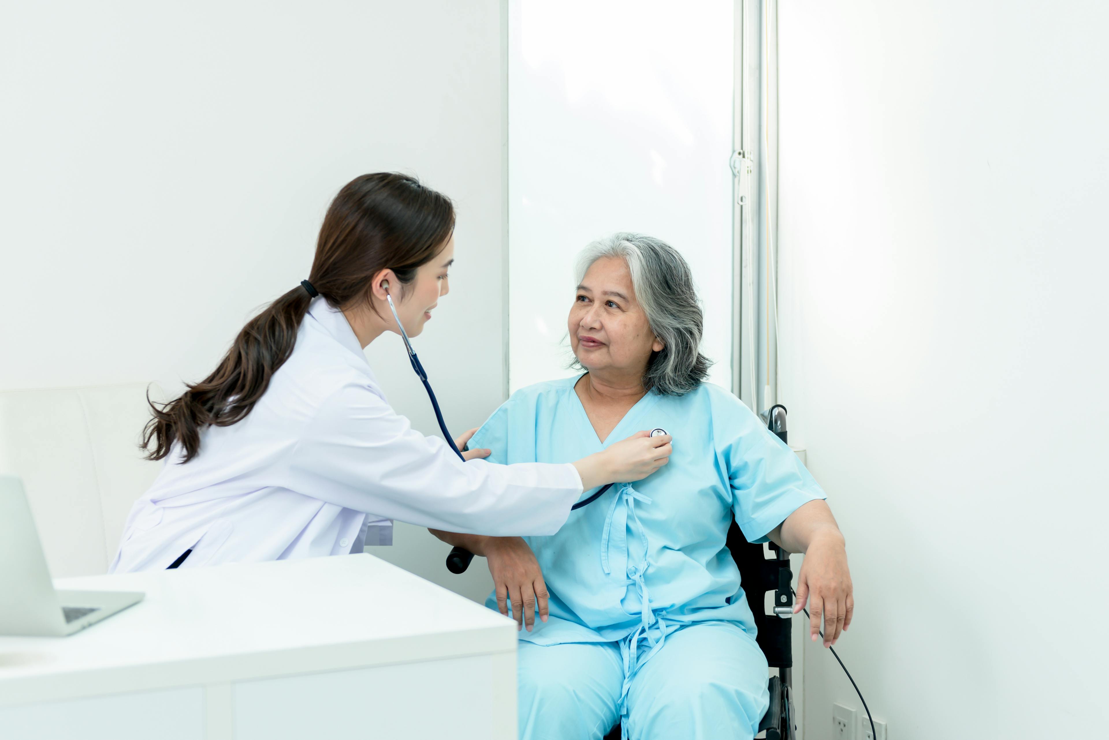 A female physician using stethoscope to examine female patient.