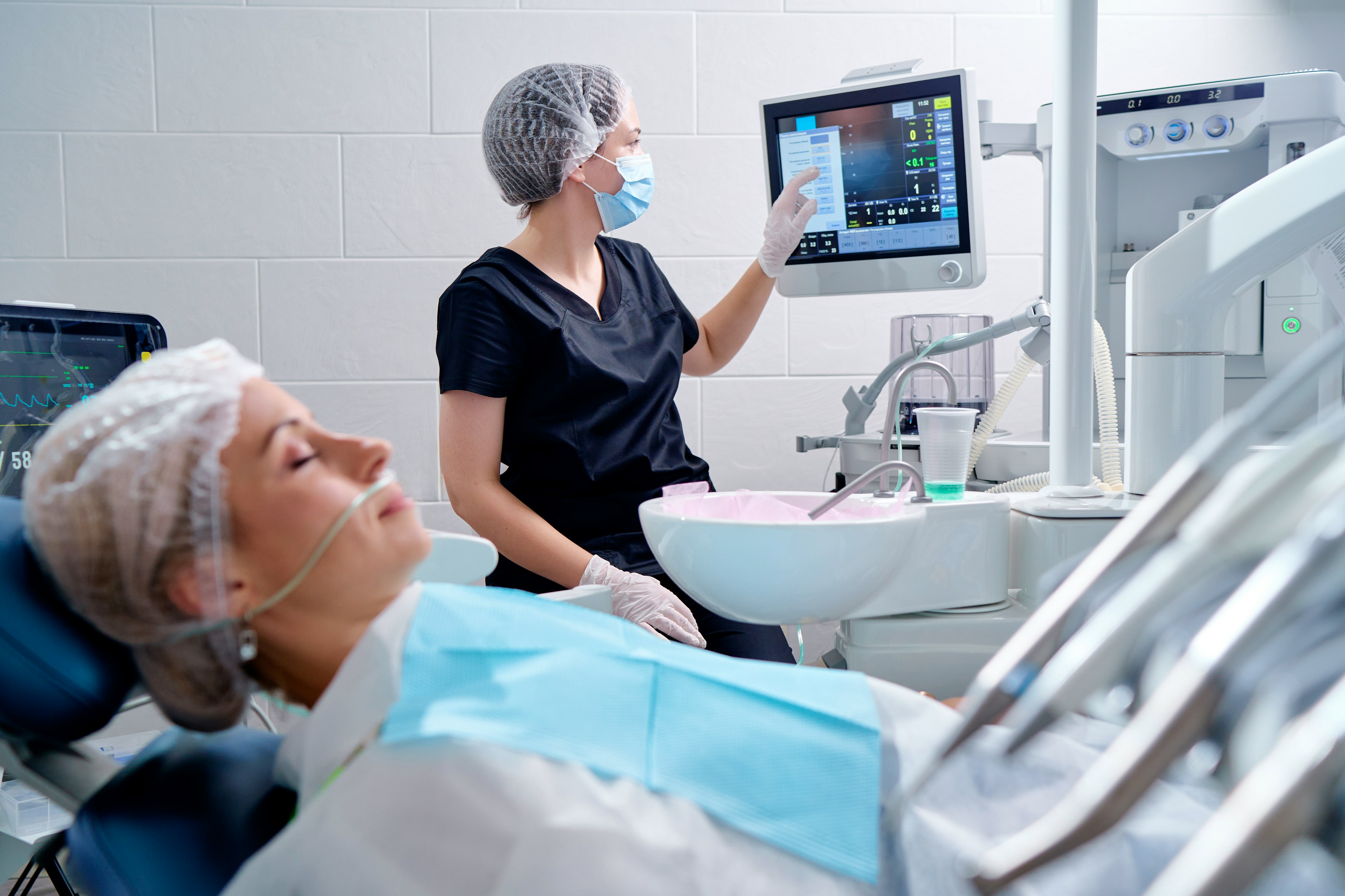 A patient undergoing a sleep exam as a sleep medicine specialist views results on screen.