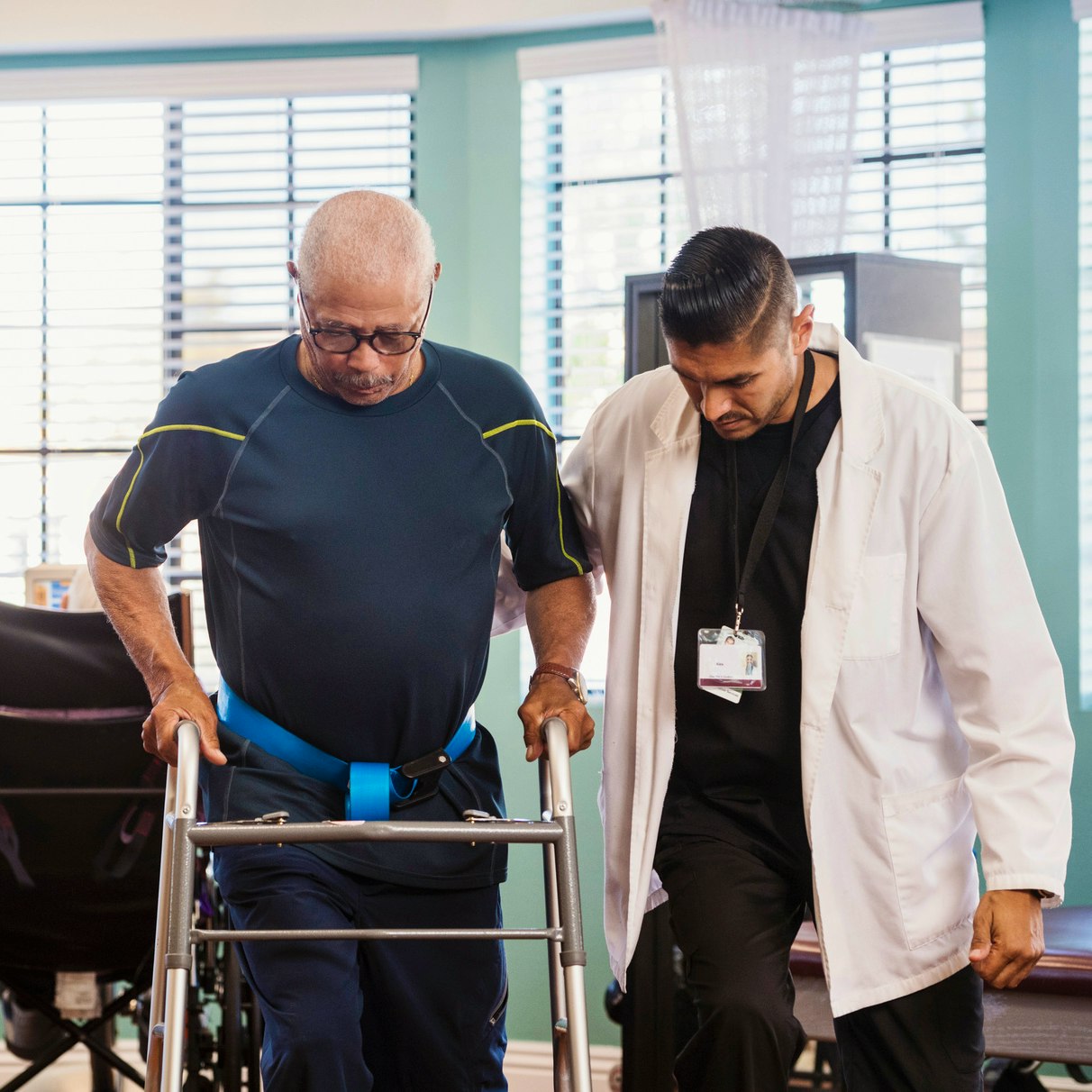 Physical therapist guiding a patient using a walker.