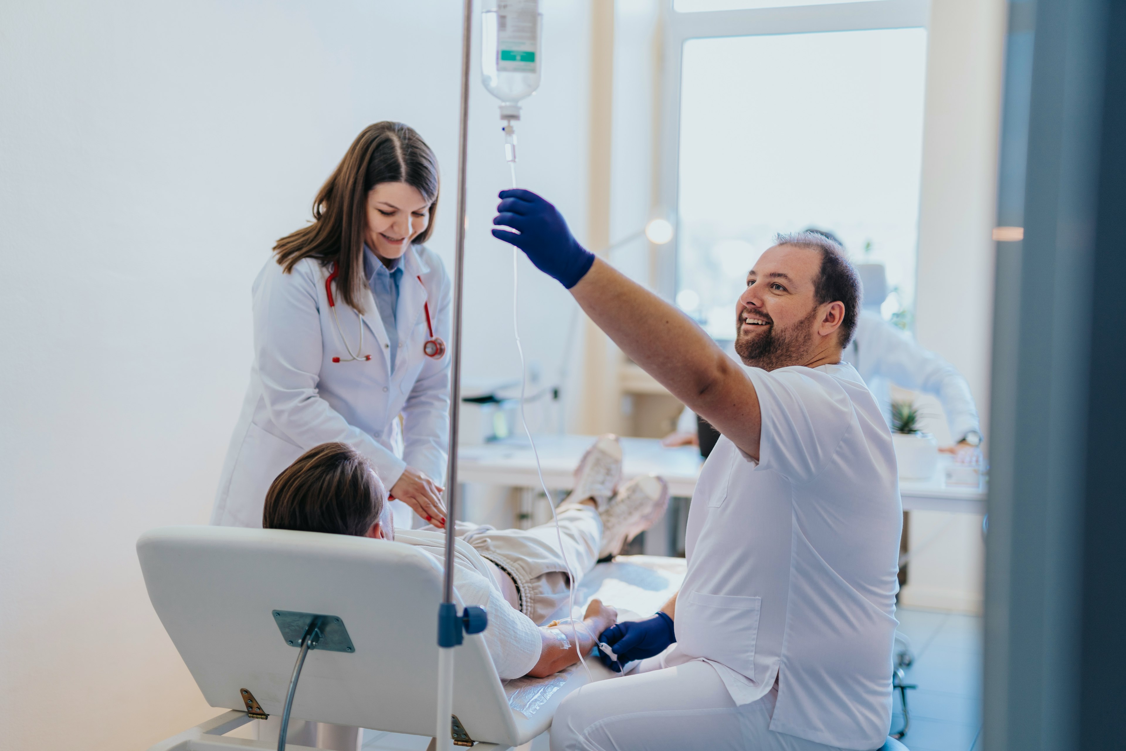 Healthcare providers delivering a medical infusion to a patient through an IV.