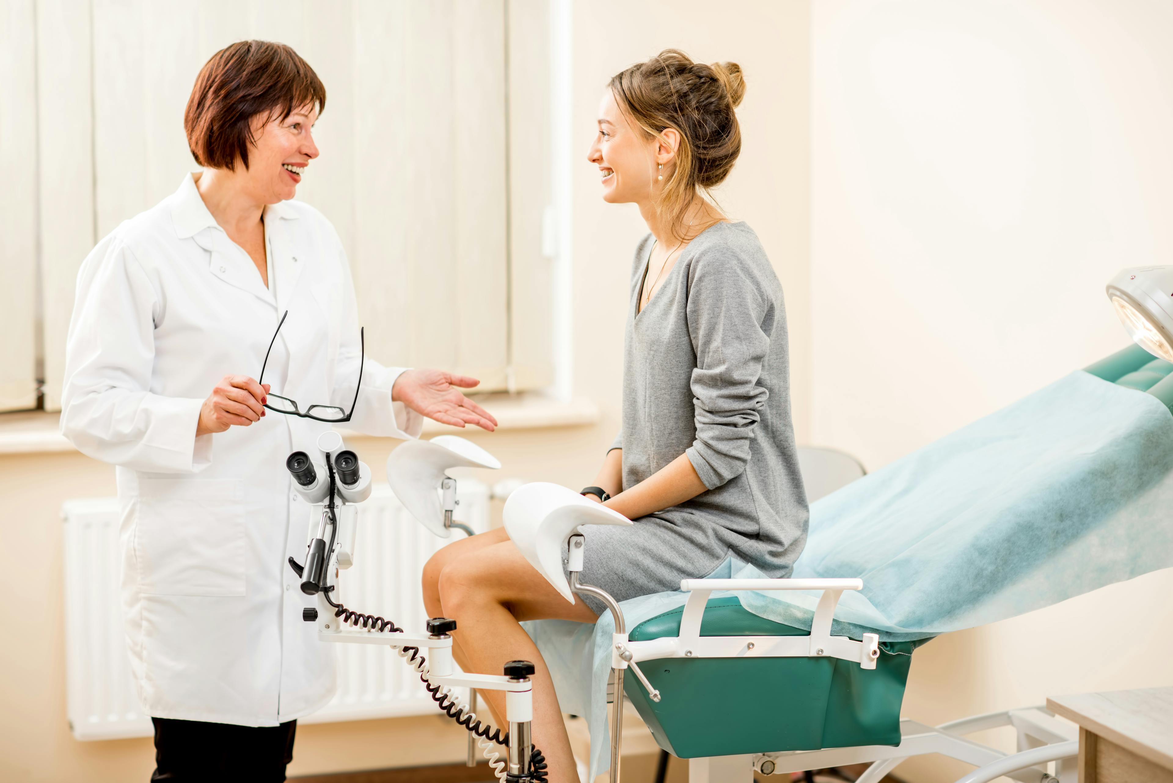 Female doctor talking to female patient on exam chair
