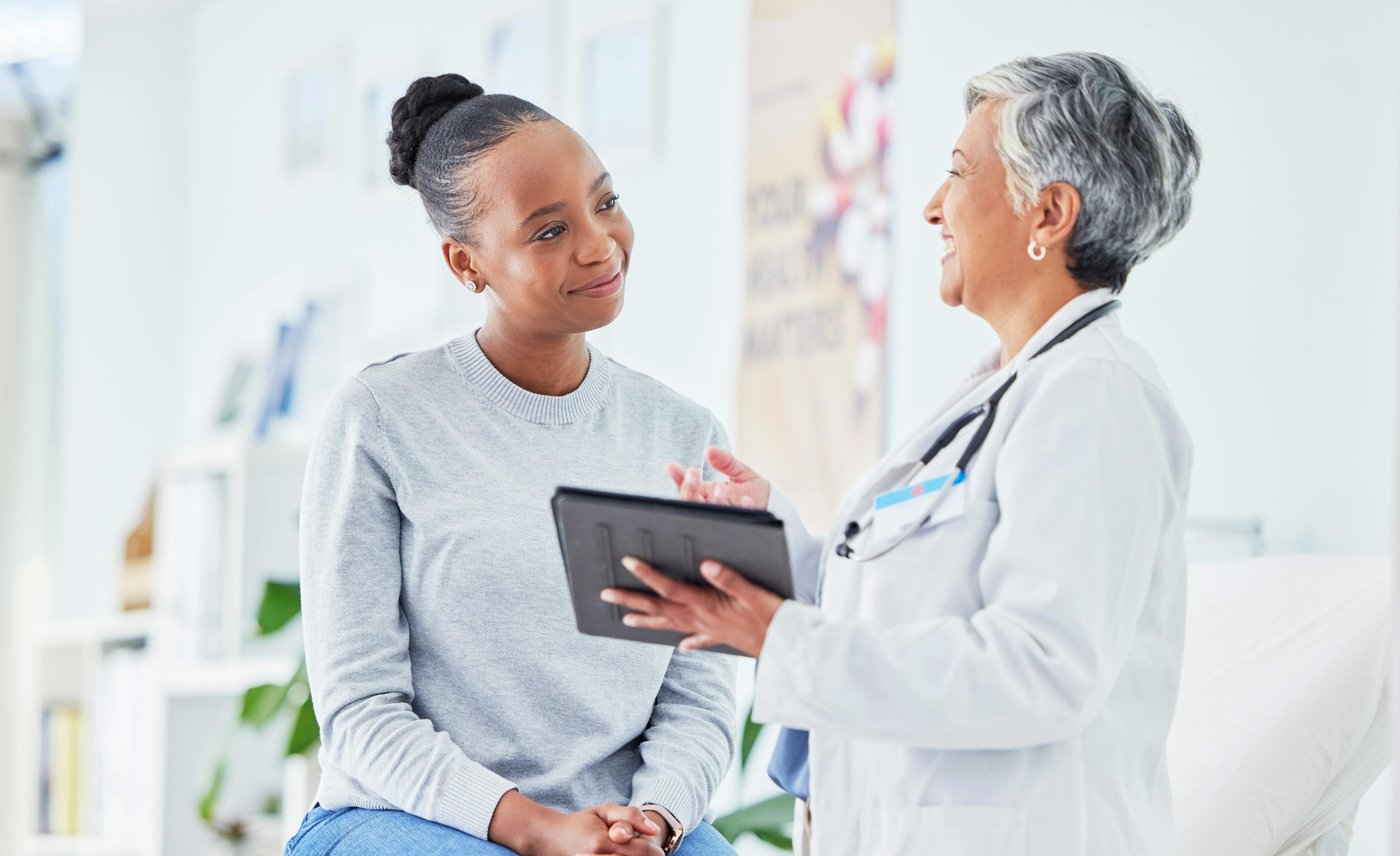 A patient is receiving care from a doctor and they are smiling together.