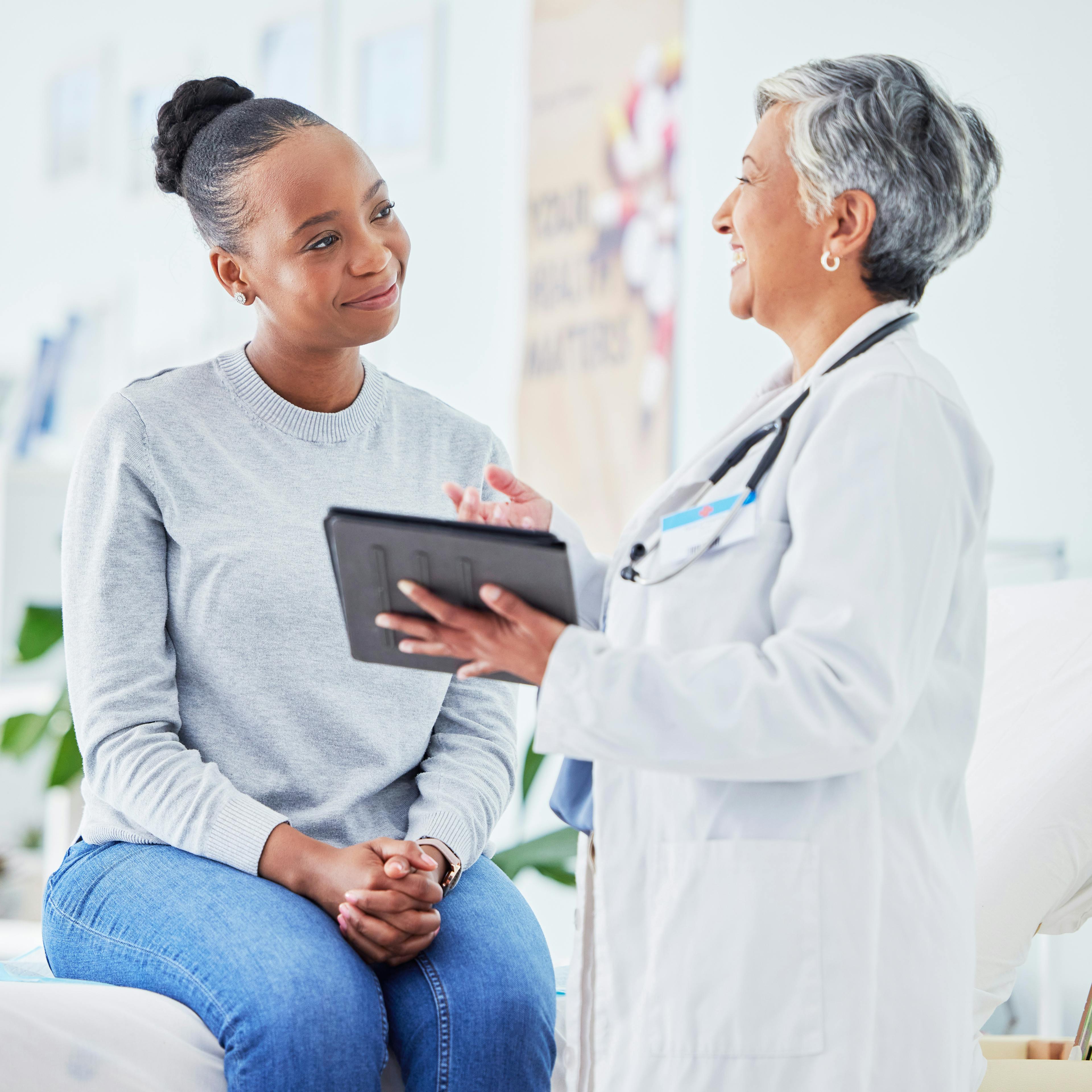 A patient is receiving care from a doctor and they are smiling together.