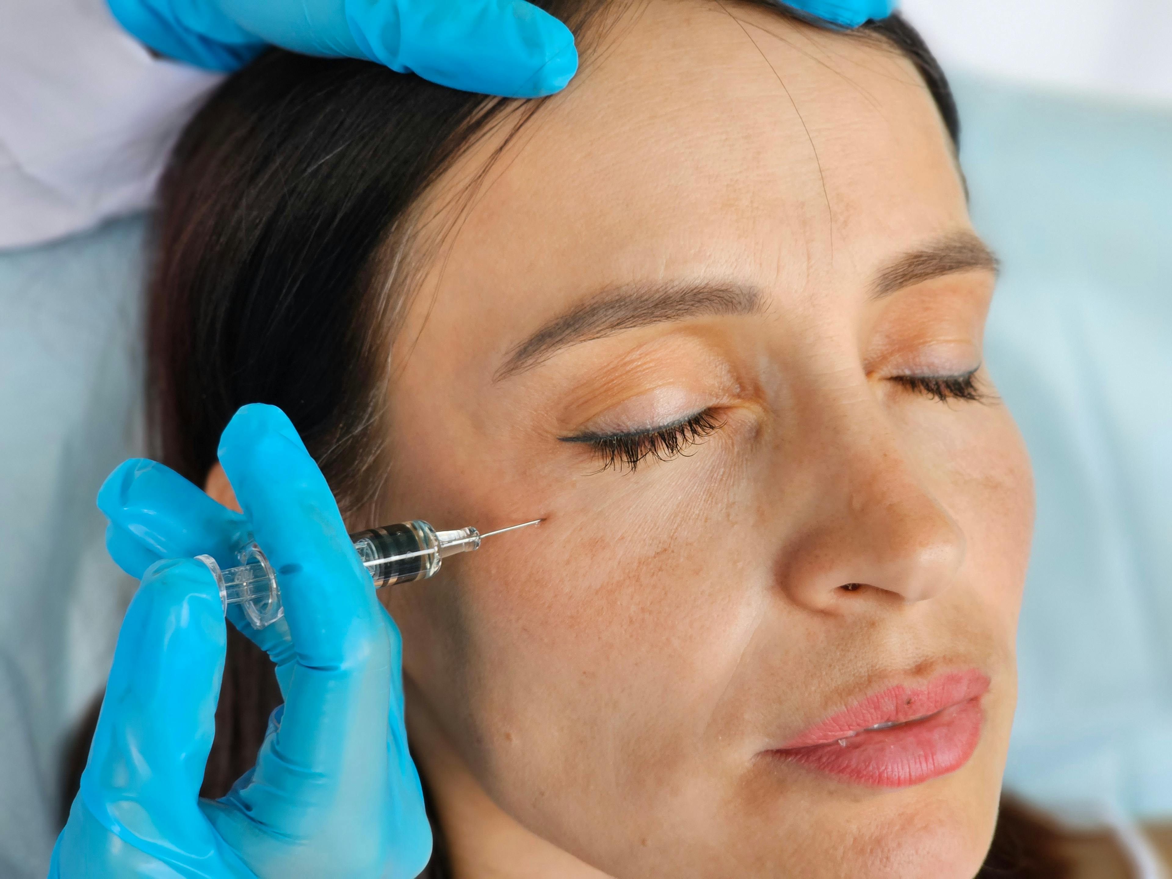 A female patient receiving a Botox injection under her right eye.