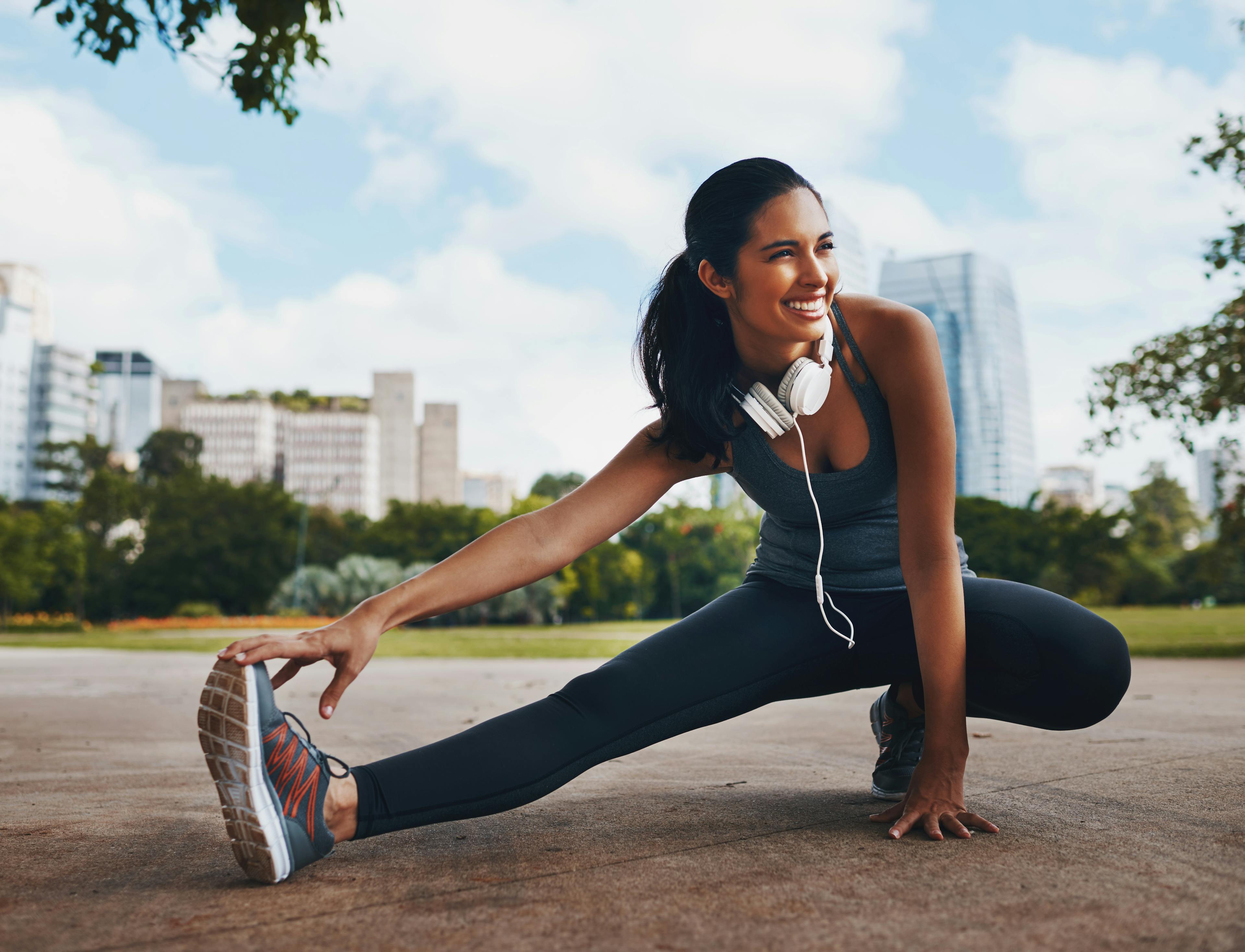 A woman stretching her feet before a run, showcasing healthy, pain-free feet after successful bunion treatment.