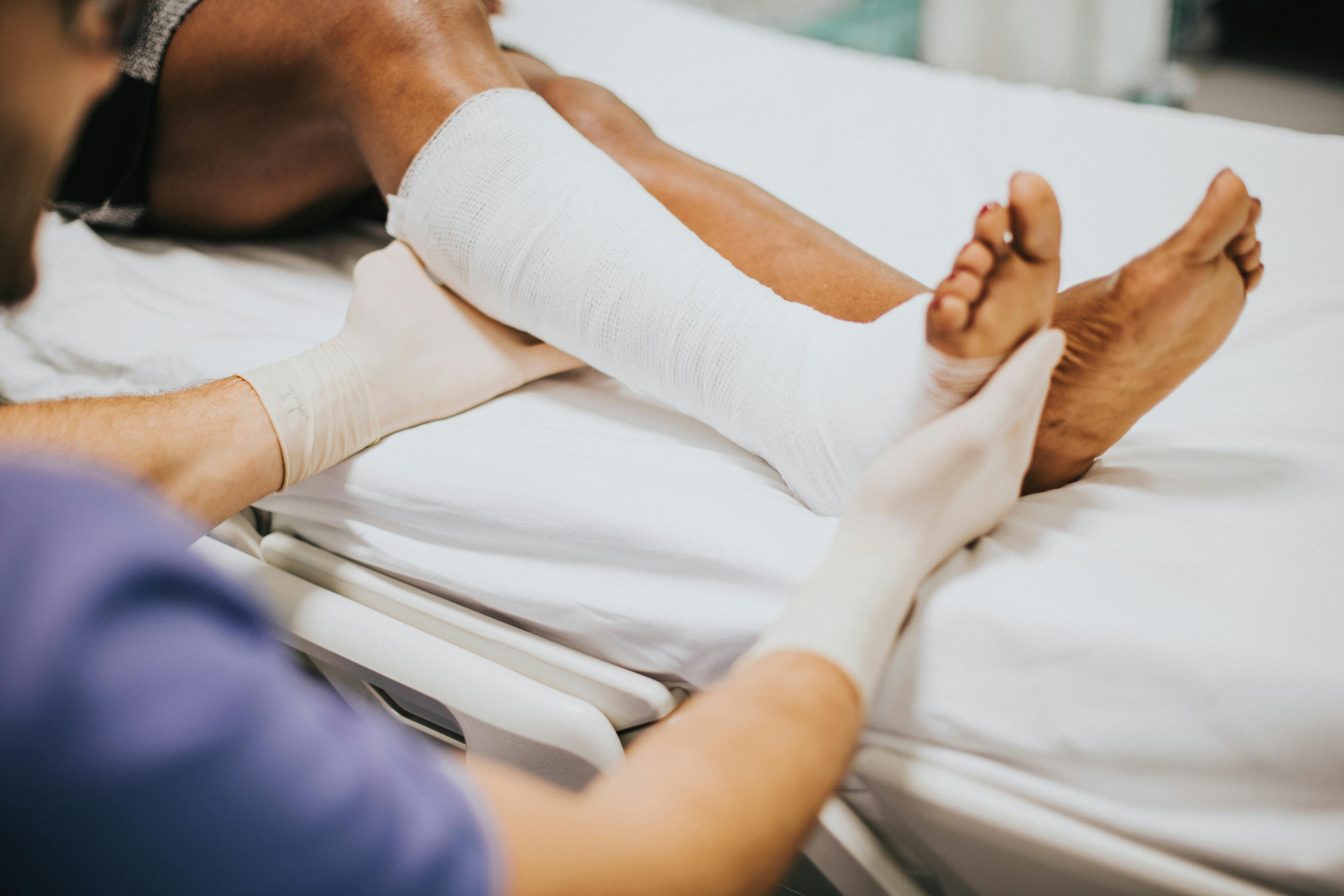 A podiatrist holding a bunion surgery patient's foot wrapped in bandages.
