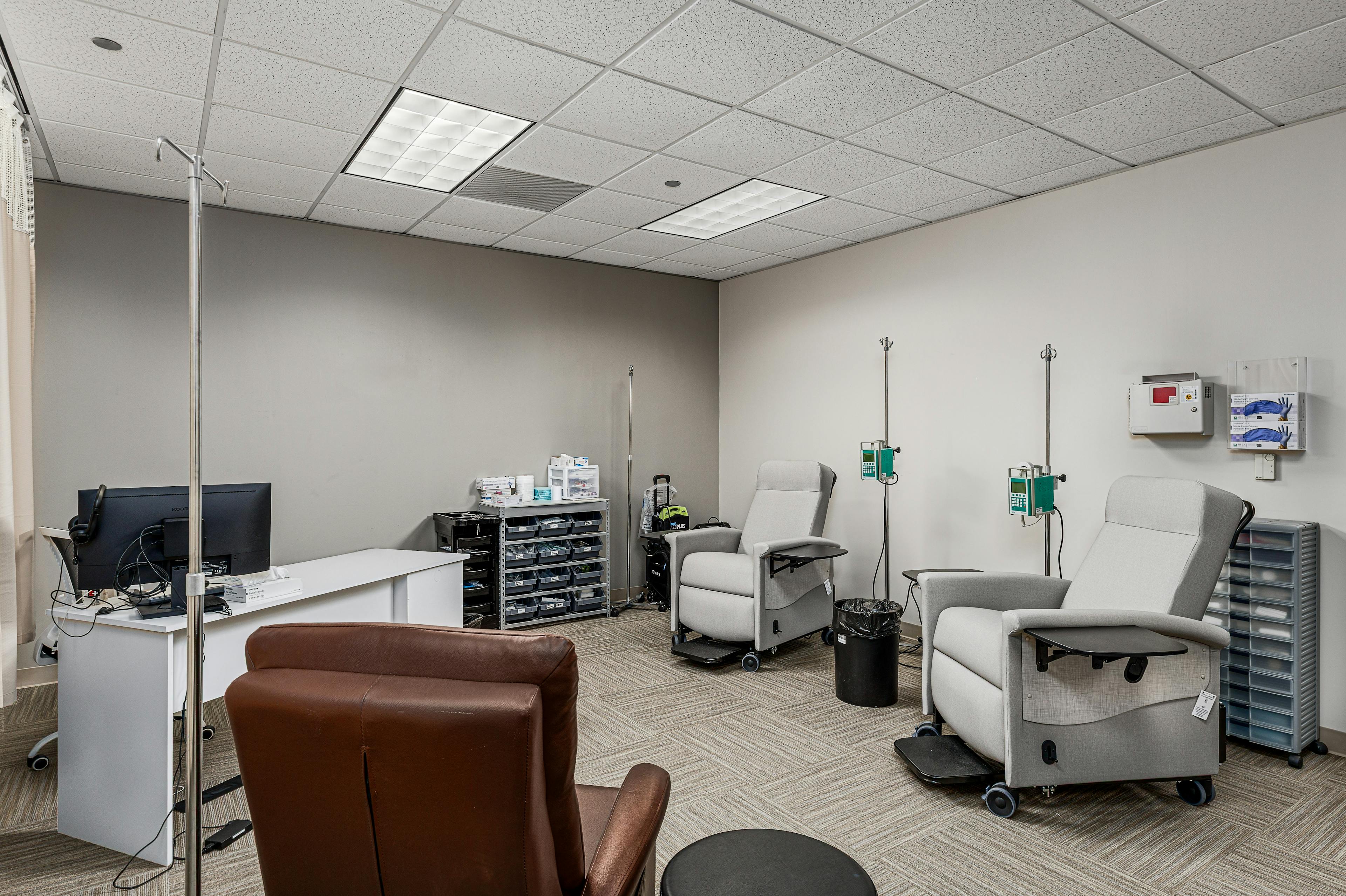 A room with comfortable recliner chairs and infusion pumps.