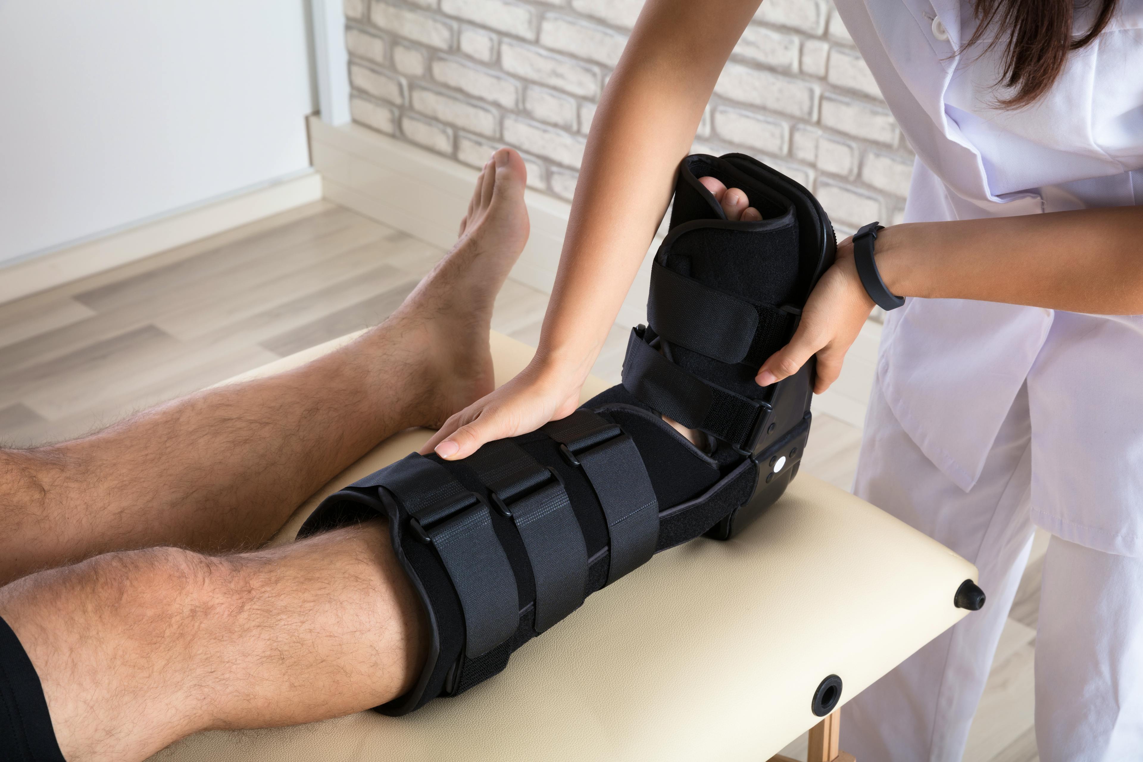 Orthopedist putting walking brace to patient's leg.