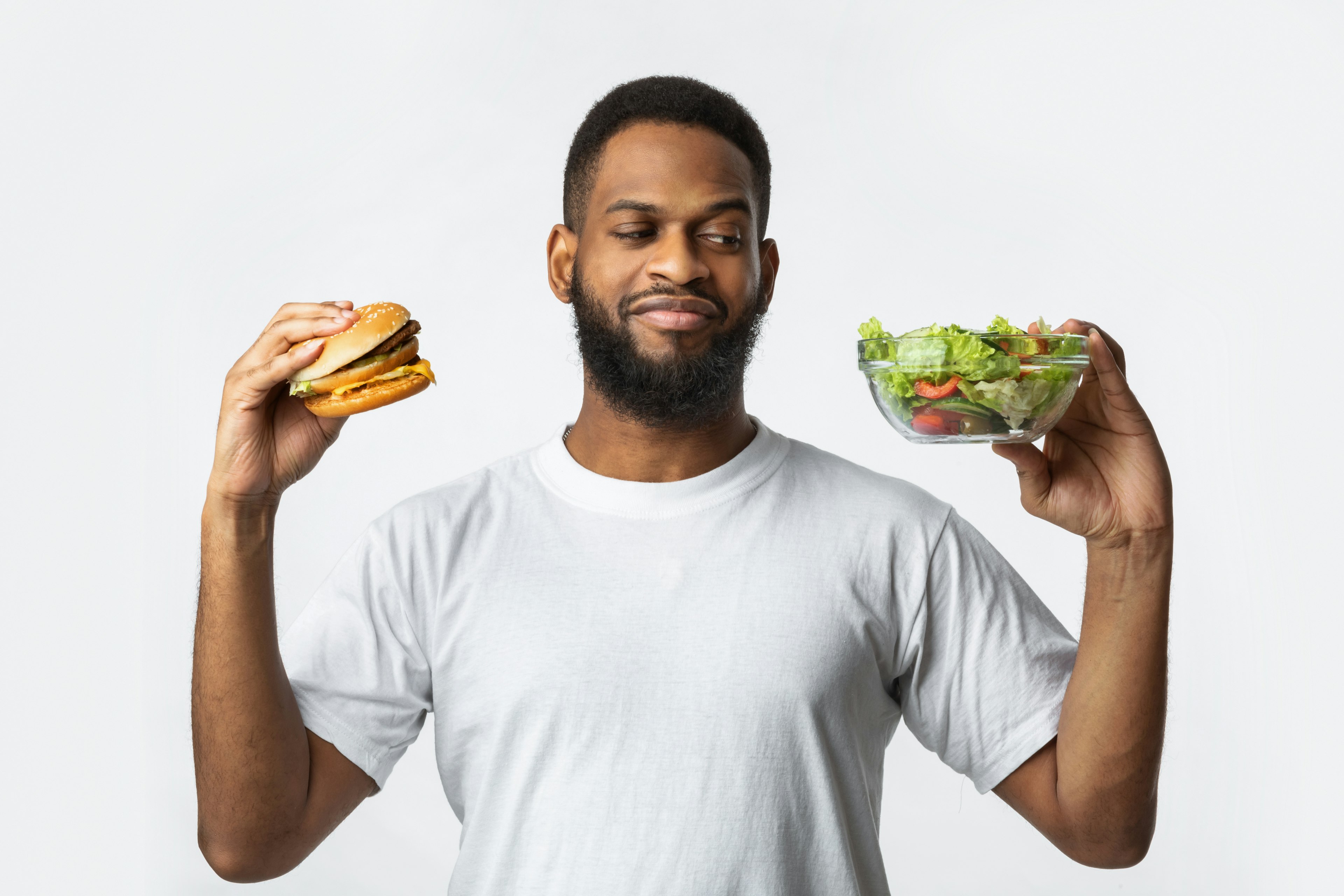 Guy Holding Burger And Salad Choosing Diet, White Background