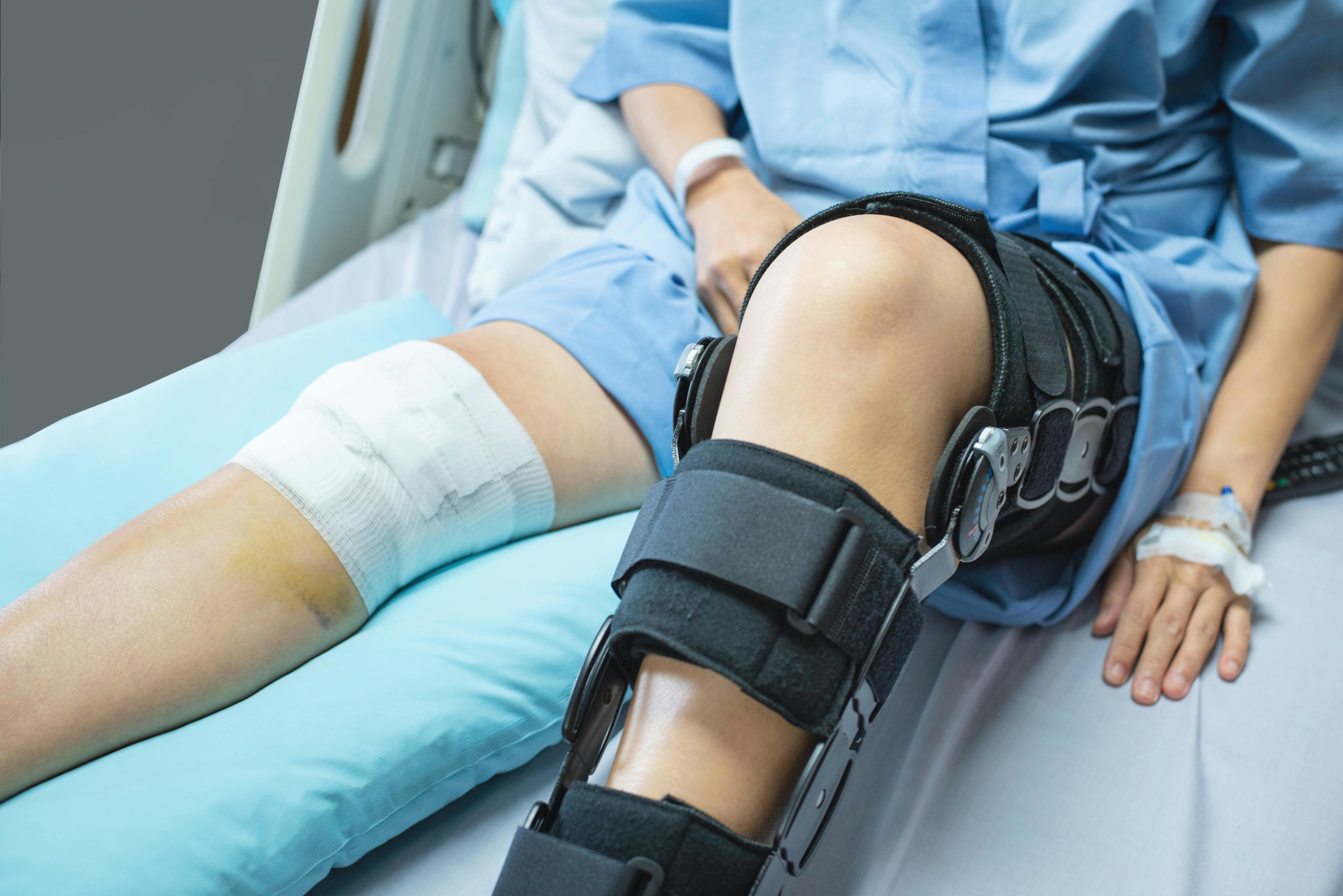 Woman patient with a bandage compression knee brace support injury on the bed.