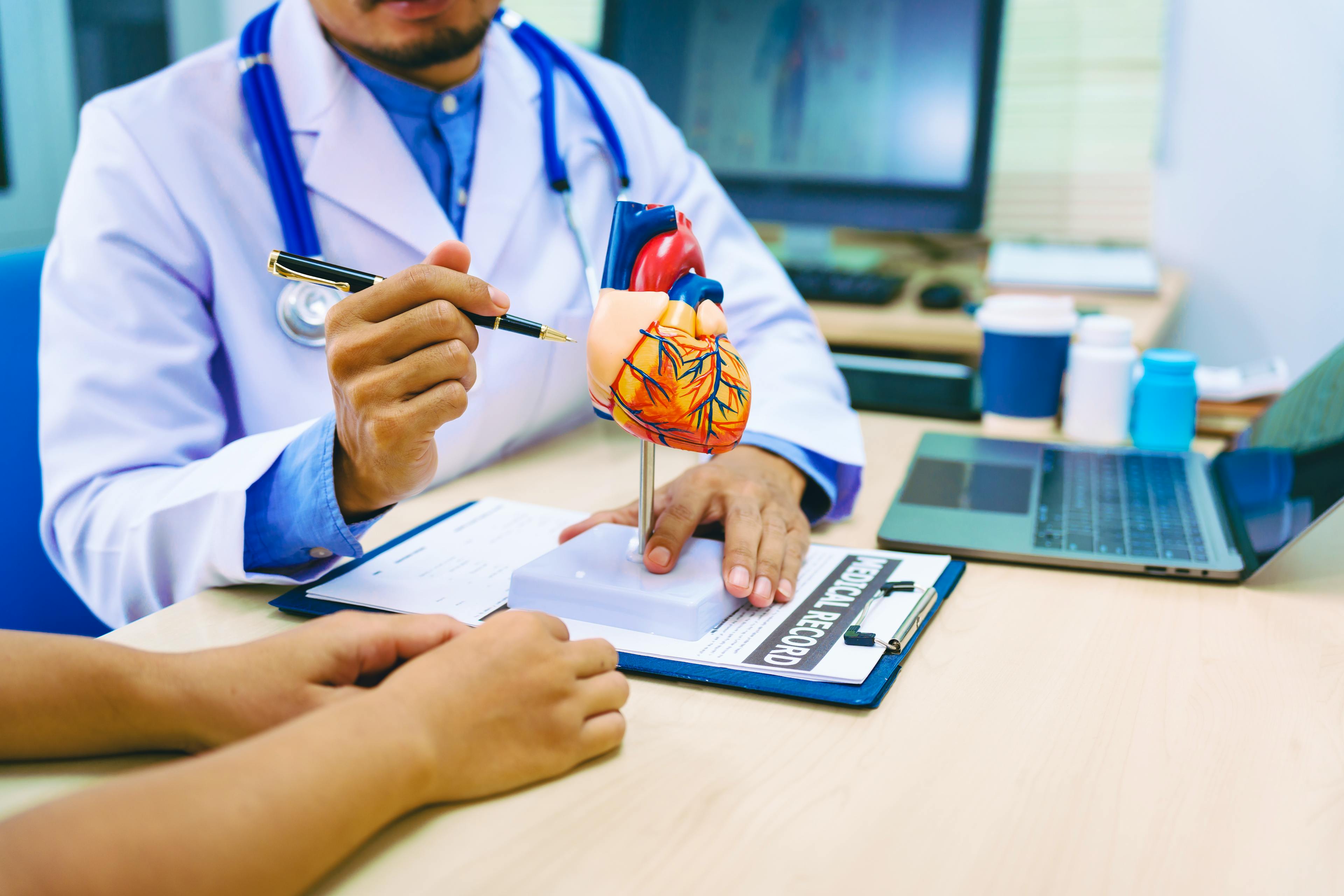 A woman with heart disease consults with a doctor at the table in a hospital. The doctor explains conditions like coronary artery disease, arrhythmia, and heart valve disease, providing advice and medication.