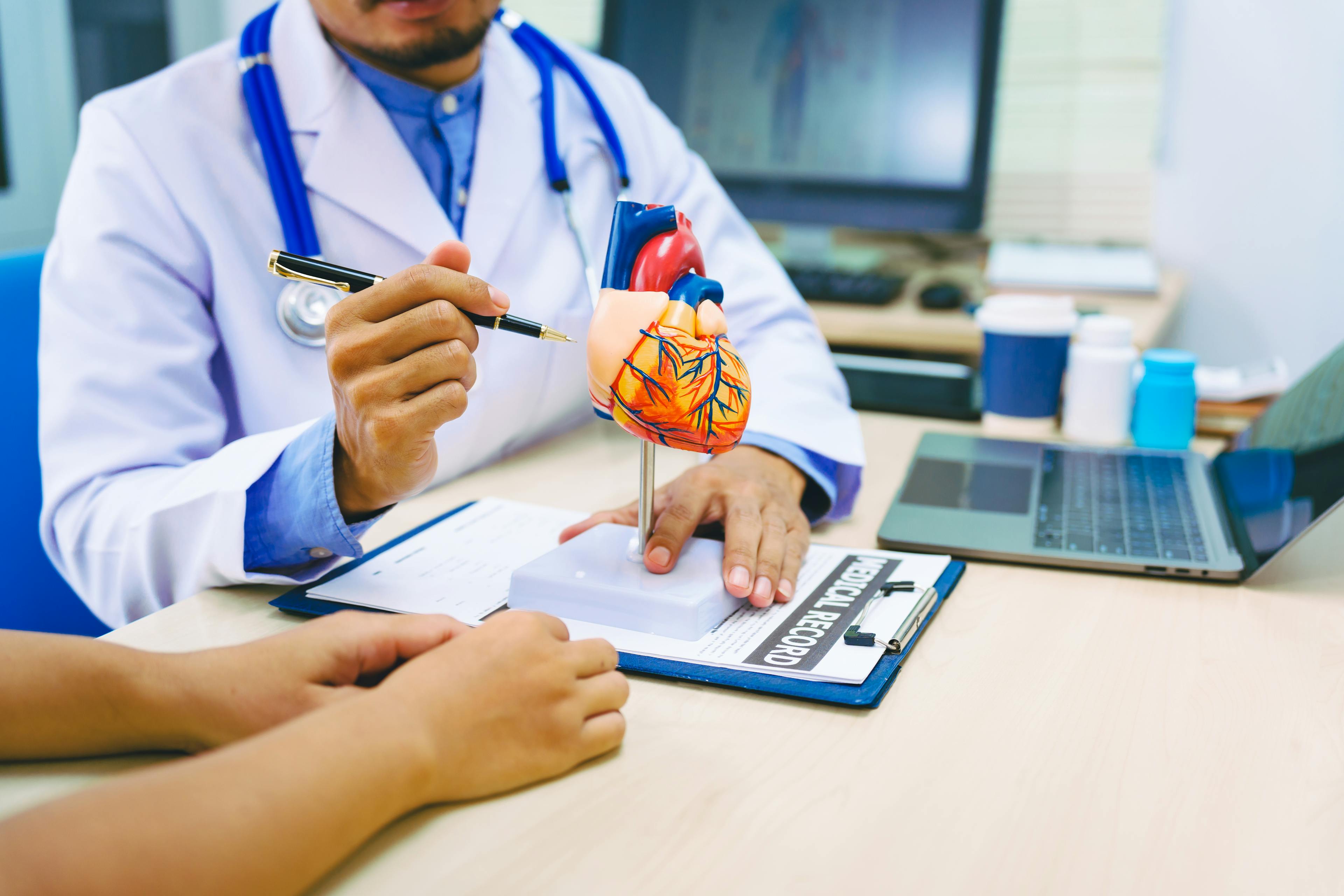 A woman with heart disease consults with a doctor at the table in a hospital. The doctor explains conditions like coronary artery disease, arrhythmia, and heart valve disease, providing advice and medication.