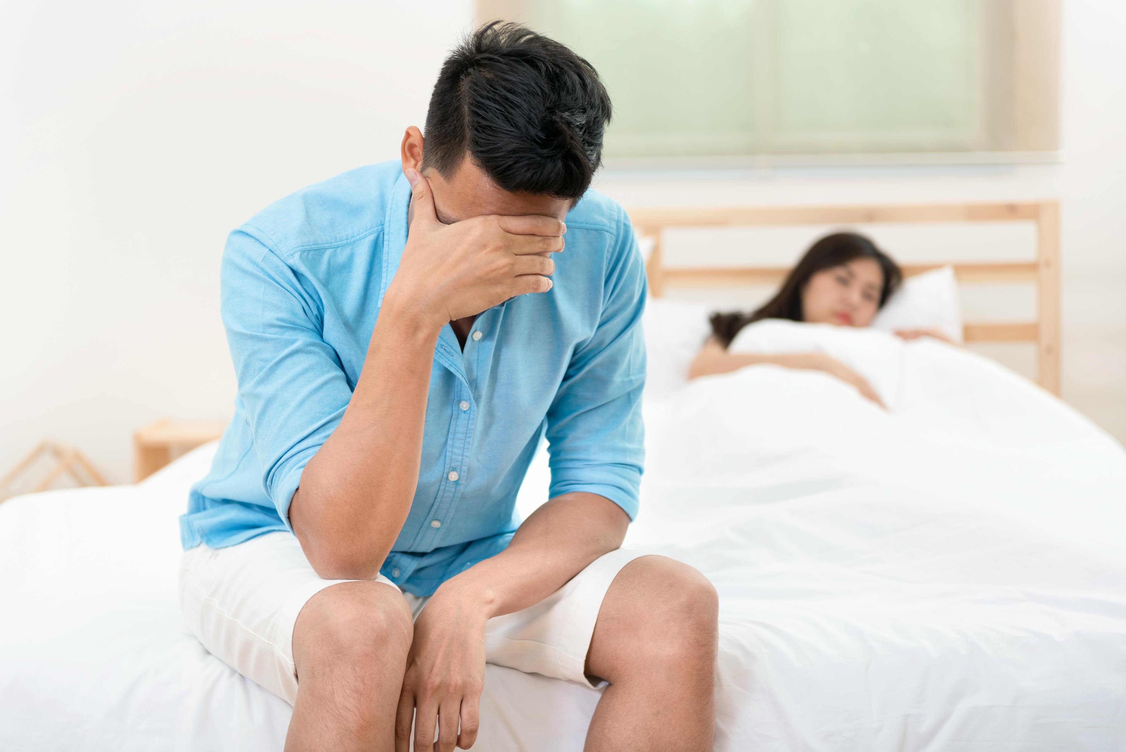 Husband unhappy and disappointed while his wife sleeping on the bed.