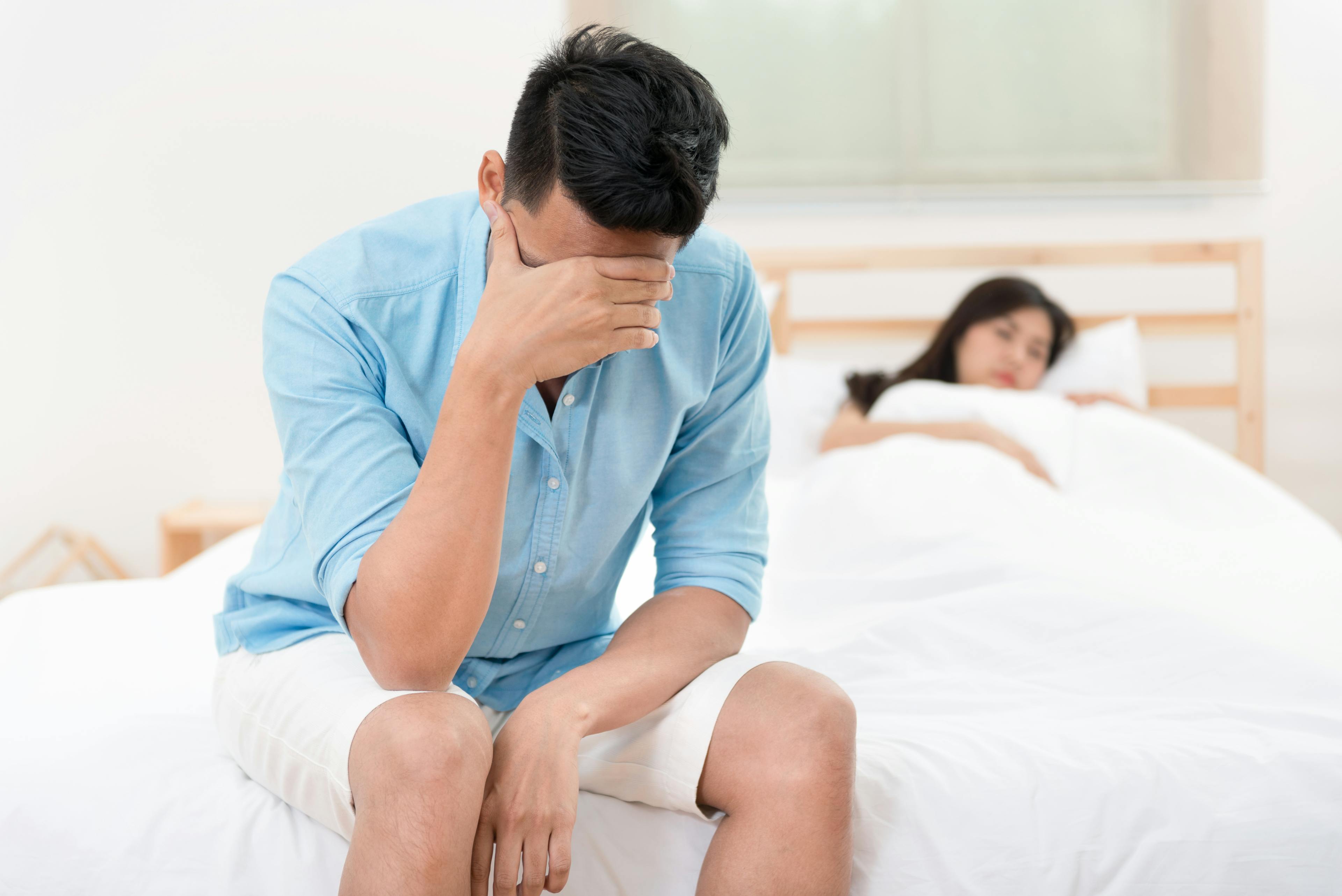Husband unhappy and disappointed while his wife sleeping on the bed.