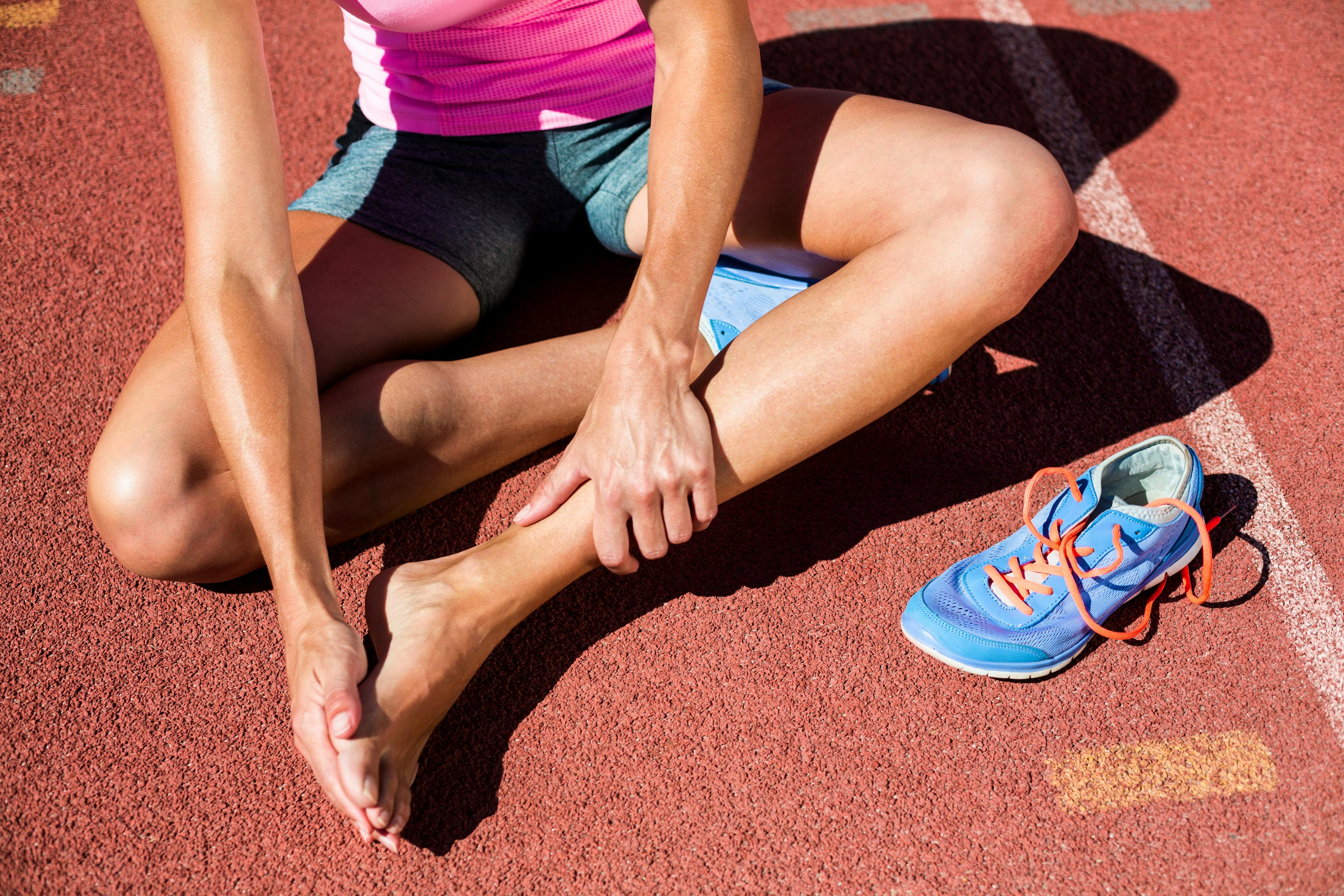 Athlete touching her bare foot without shoes.