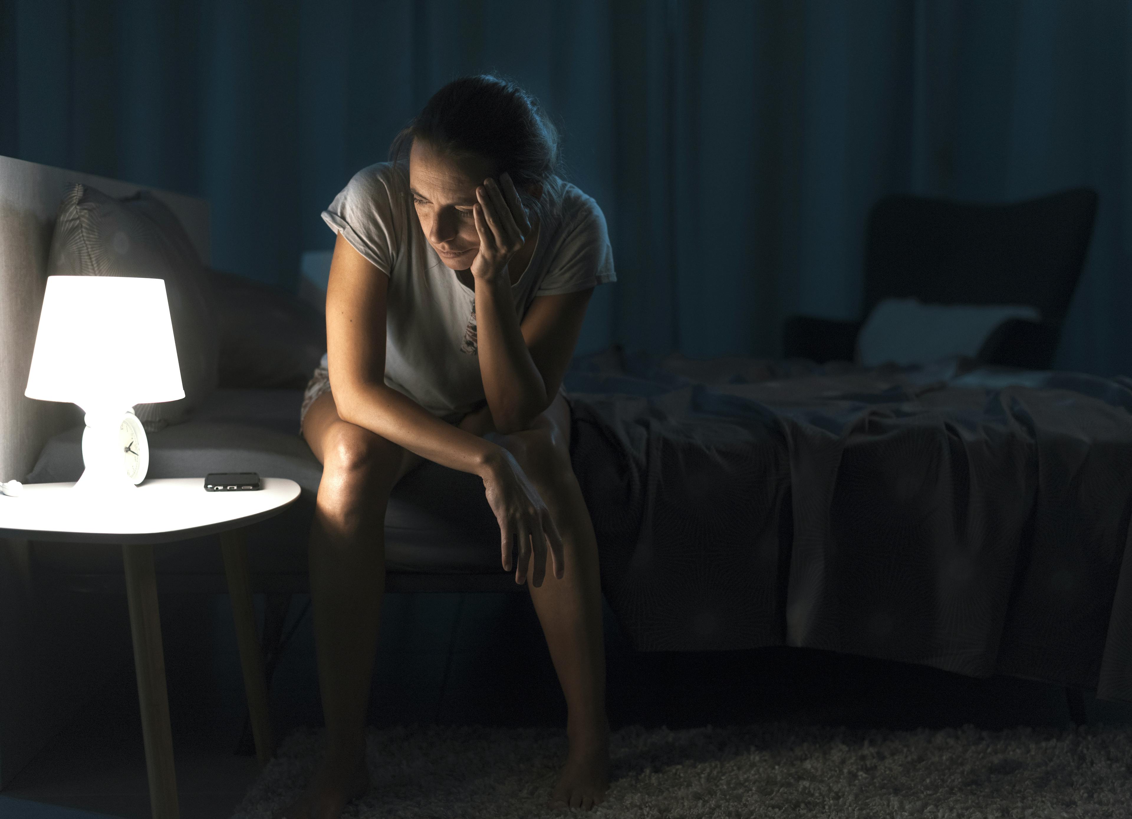A person with their hand to their face, stressed due to insomnia.