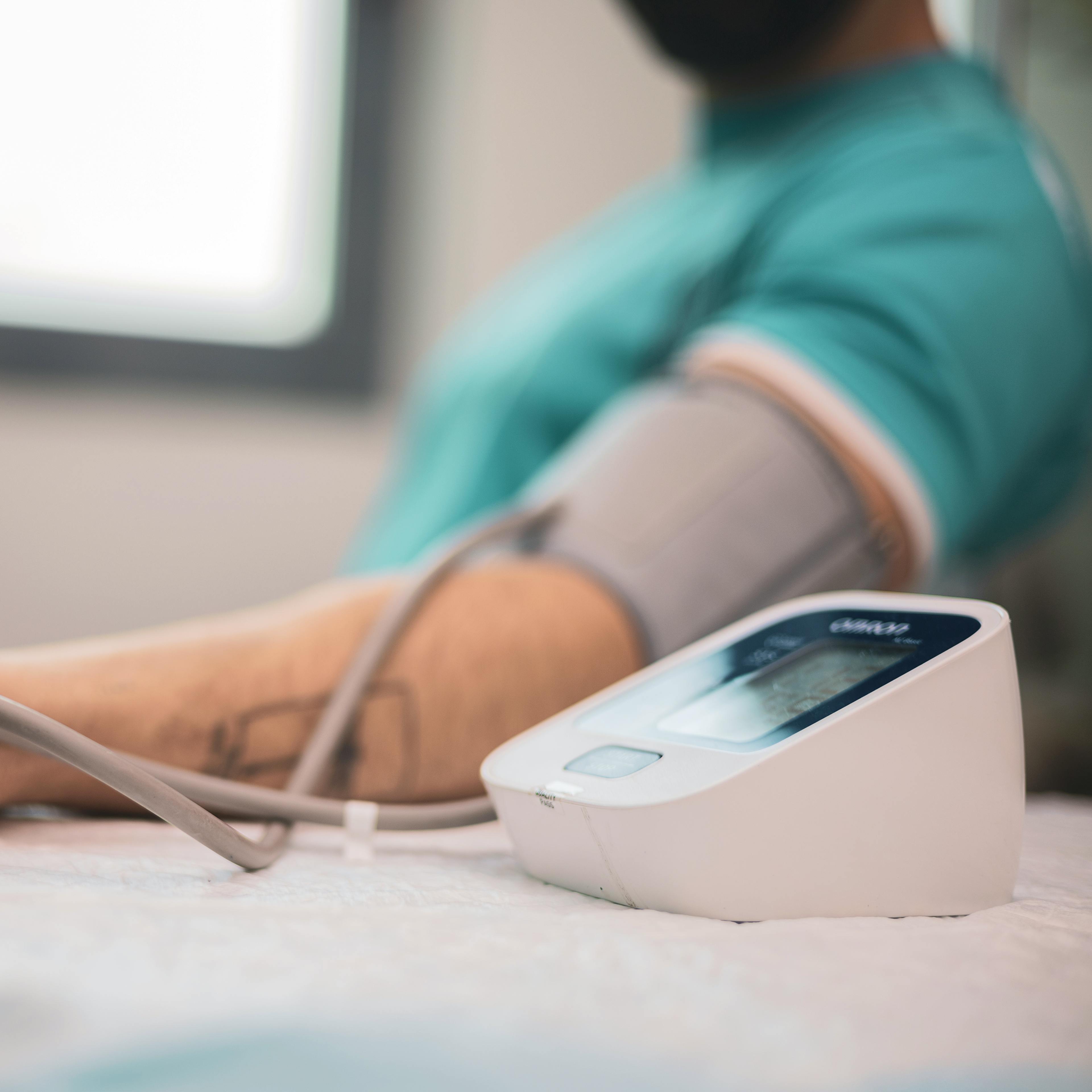 Doctor taking blood pressure and pulse on the arm of a patient with high cholesterol in the clinic