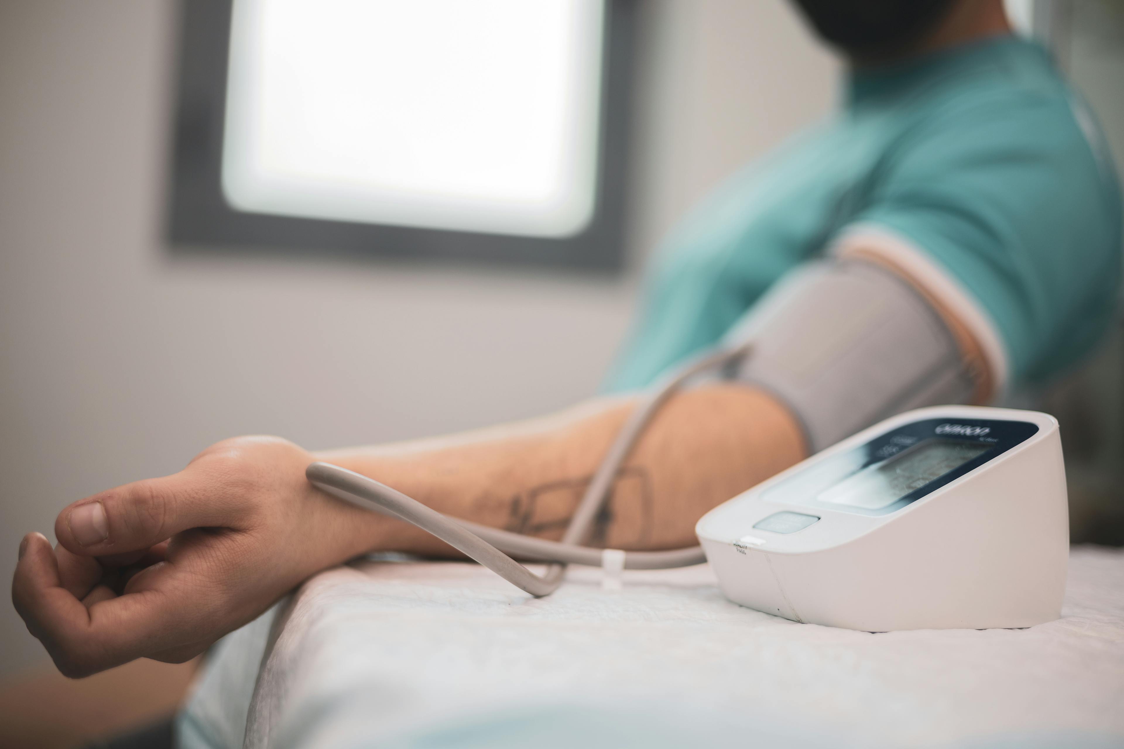 Doctor taking blood pressure and pulse on the arm of a patient with high cholesterol in the clinic
