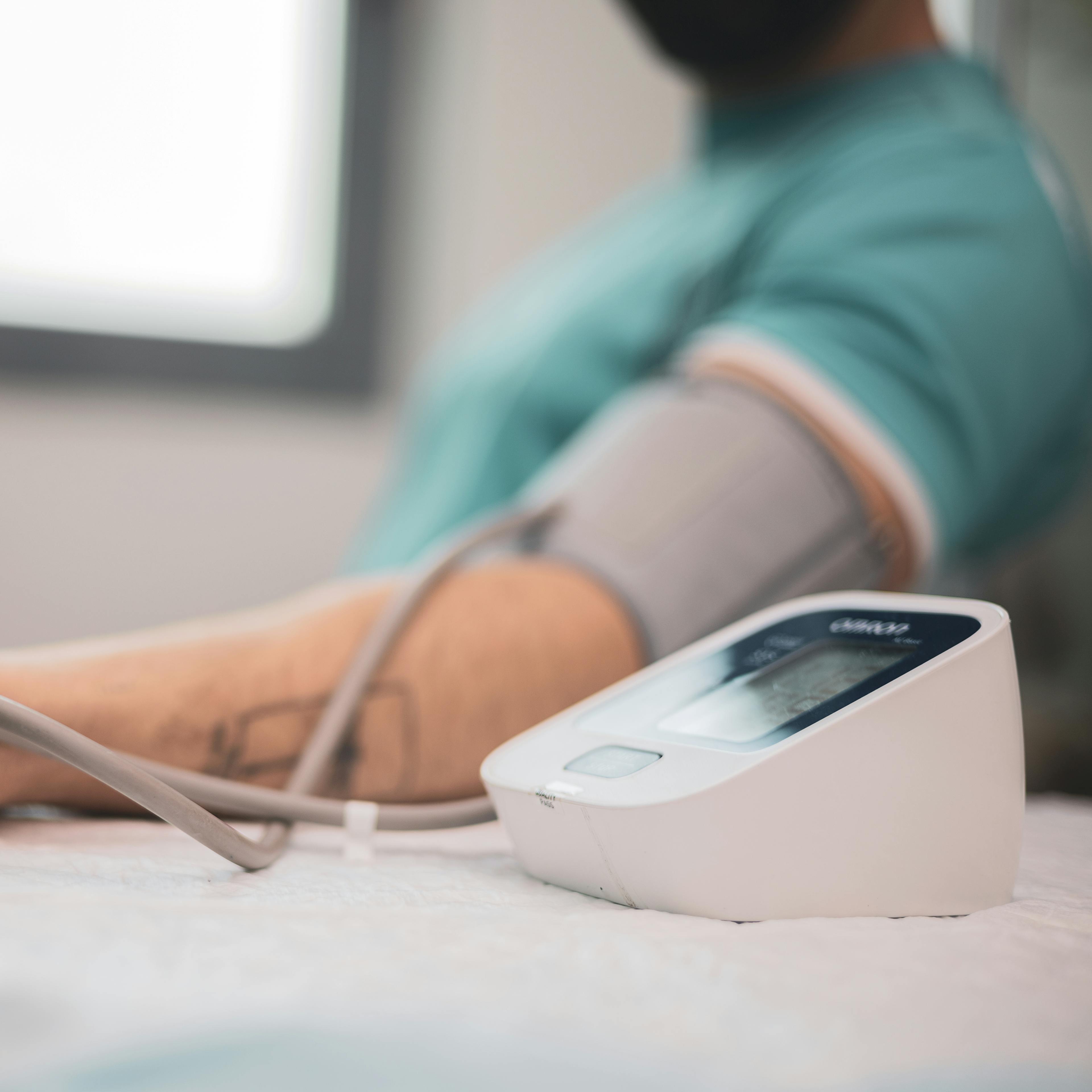 Doctor taking blood pressure and pulse on the arm of a patient with high cholesterol in the clinic