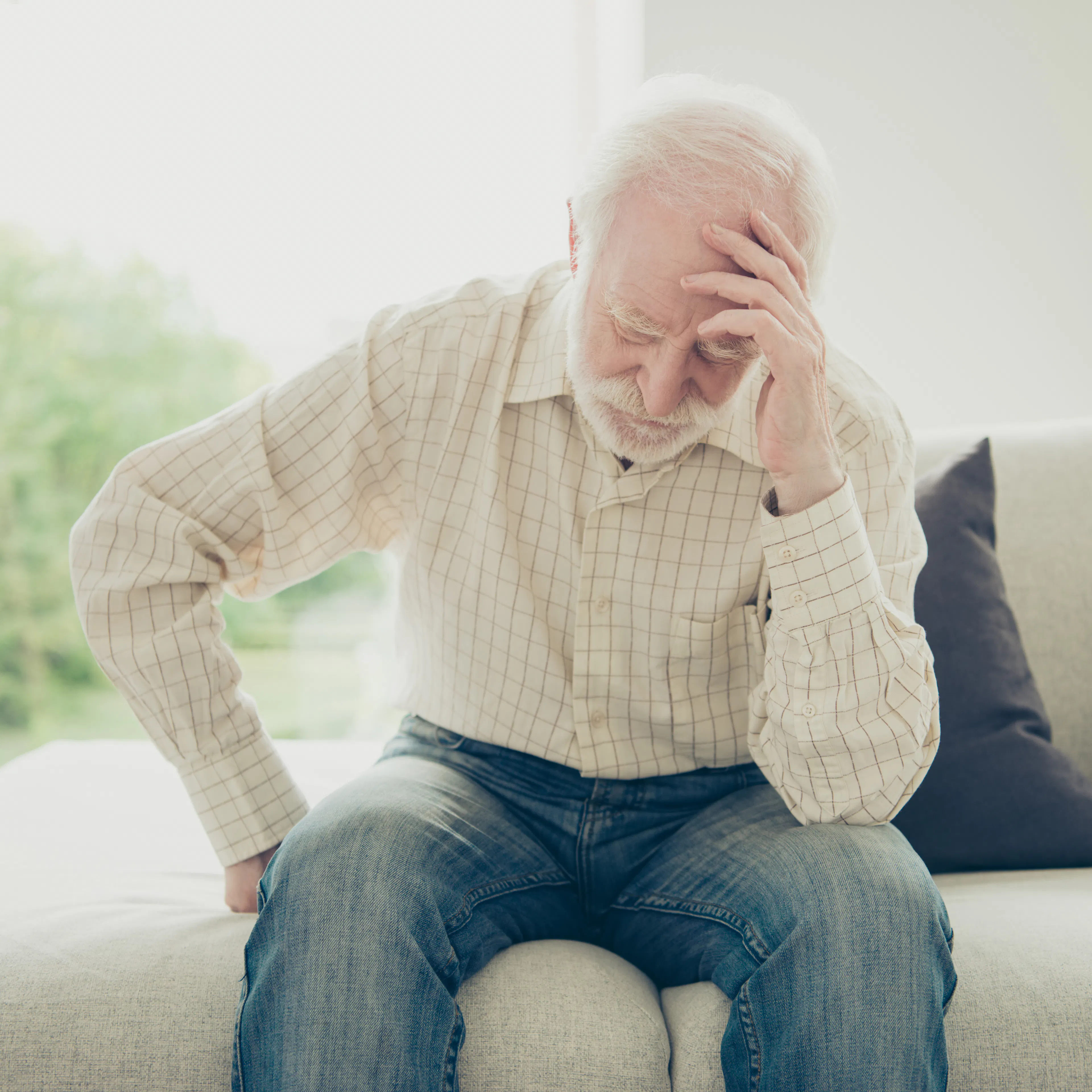 An elderly man is holding his head in pain.