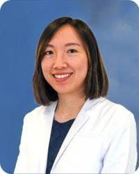 Endocrinologist, Nicole Sheung, DO, posing for her headshot in her white coat.